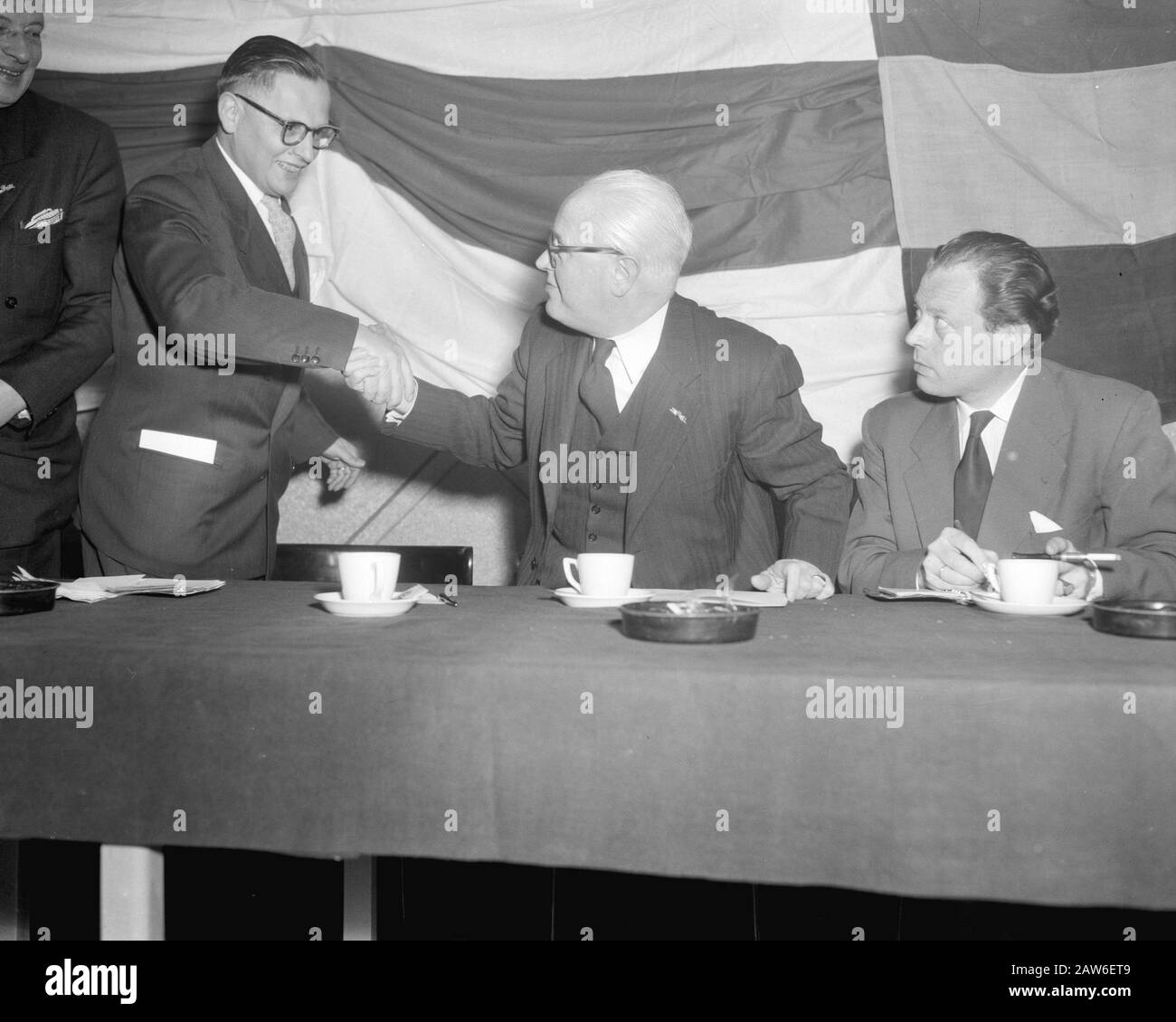 Protesttreffen für russische Invasion in Ungarn in den Twentehallen in Enschede. Referenten mr. CPM Romme (sitzend) und E.A. Vermeer (links) Shake Hands Datum: 4. November 1956 Ort: Enschede Schlüsselwörter: Meetings Personenname: Romme, CPM, Vermeer, Evert Stockfoto