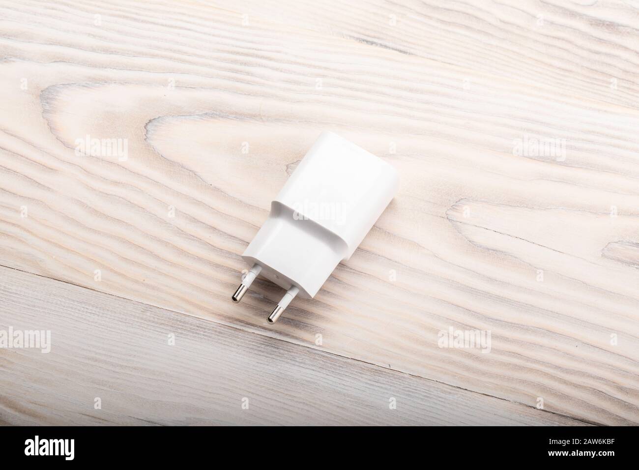 Smartphone-Akkuladegerät auf Holztisch. Schaltnetzteil, Ladestromversorgung für Telefon. Stockfoto
