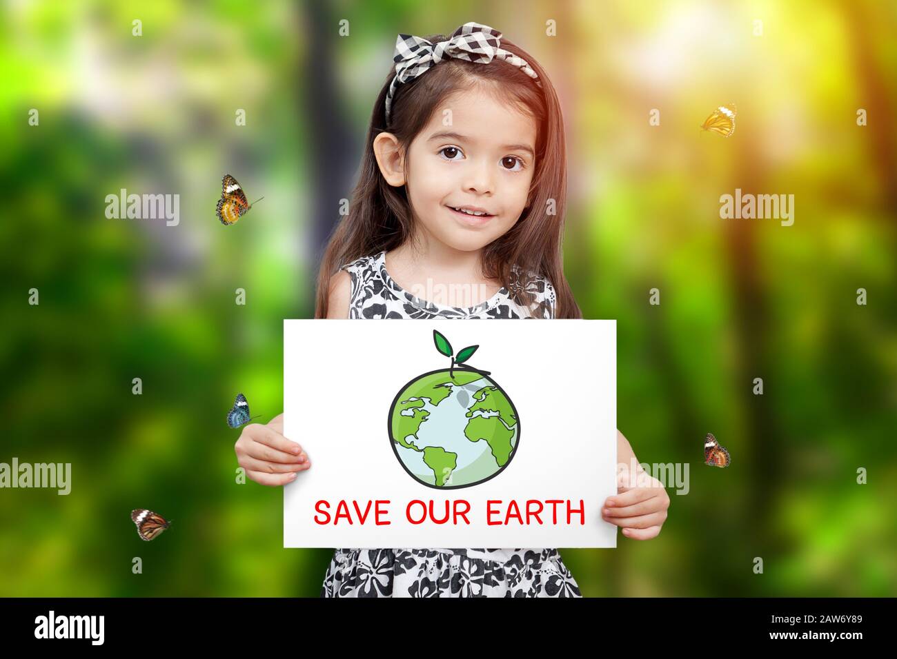 Kinder halten Papier, das Erde zeichnet, und grünes Sämlingwachstum und Wort speichern unsere Erde mit grünem Baumhintergrund und Schmetterling herumfliegen. Kinder c Stockfoto