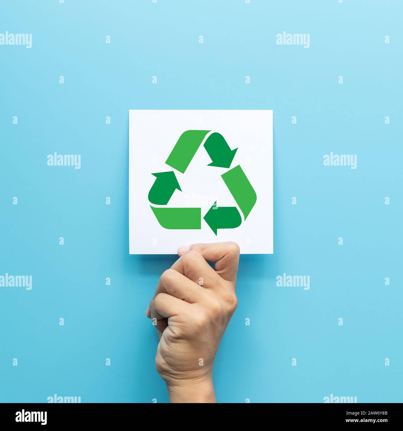 Grünes Recycling-Symbol auf der weißen Papierkarte in der Hand isoliert auf blauem Hintergrund grünes Geschäftskonzept für Umweltbewusstseinsunternehmen Stockfoto