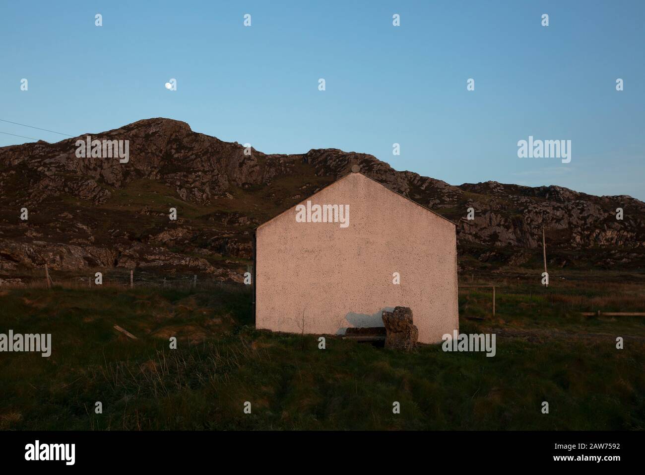 Das giebelständige Ende eines Cottages, das bei Sonnenuntergang auf der Inneren Hebrideninsel Colonsay an der schottischen Westküste abgebildet ist. Die Insel liegt im gebiet des rates von Argyll and Bute und hat eine Fläche von 4.074 Hektar (15,7 sq mi). Auf einer Südwest- bis Nordostachse ausgerichtet, misst sie 13 km Länge und erreicht an ihrer breitesten Stelle 3 Meilen (4,8 km), 2019 hatte sie eine ständige Population von 136 Erwachsenen und Kindern. Stockfoto