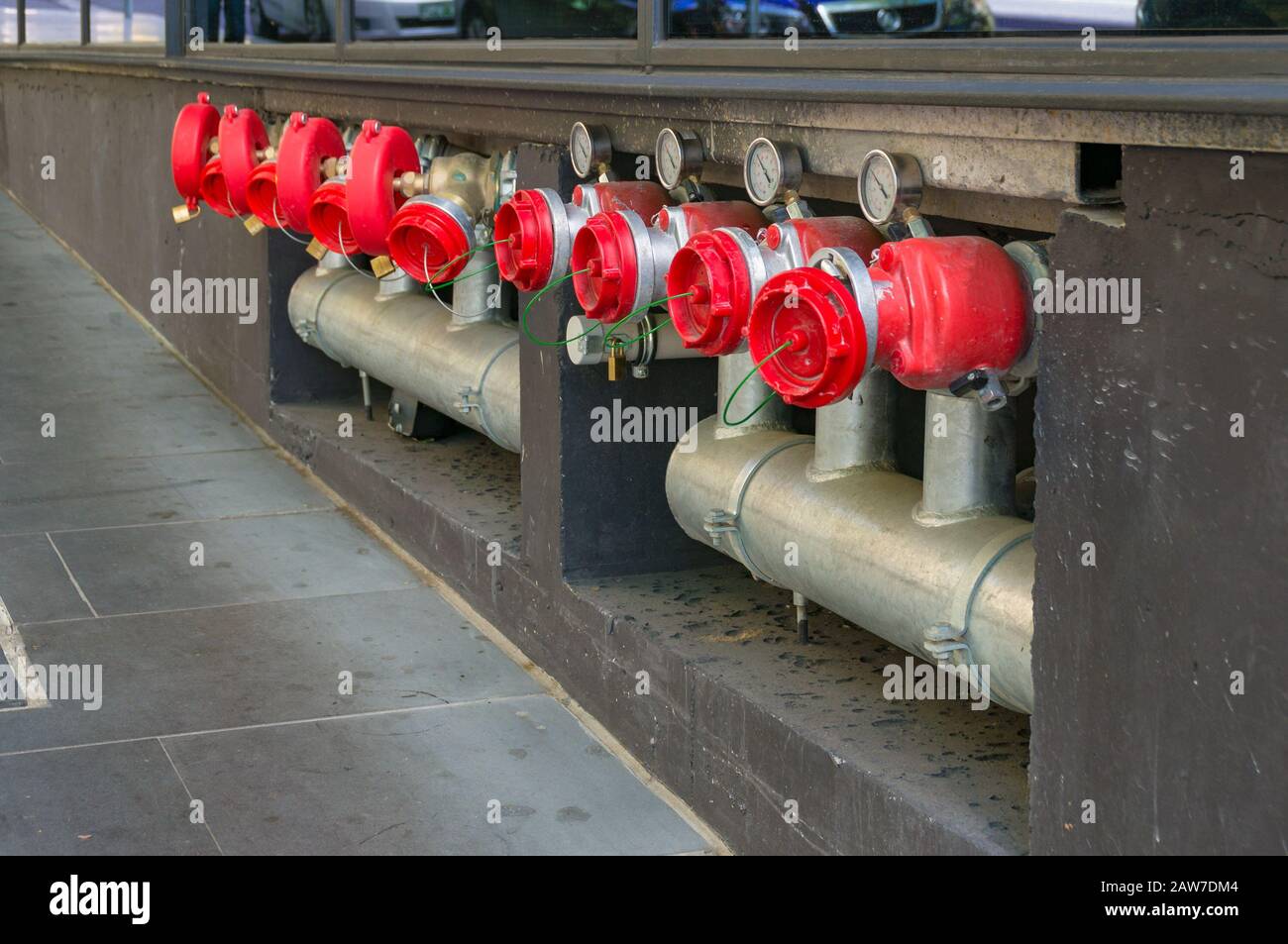 Helle Hydrantenbooster in einer Reihe mit Metallrohren und roten Kappen. Industrielle städtische Infrastruktur Stockfoto