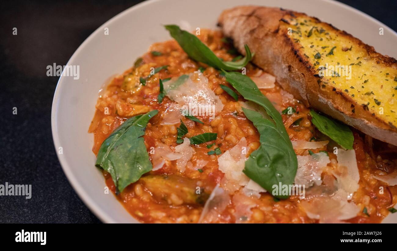 Nahaufnahme von gebratenem Reis mit Tomatensauce. Reis mit Grüns und einem Stück Brot auf dem Teller. Stockfoto