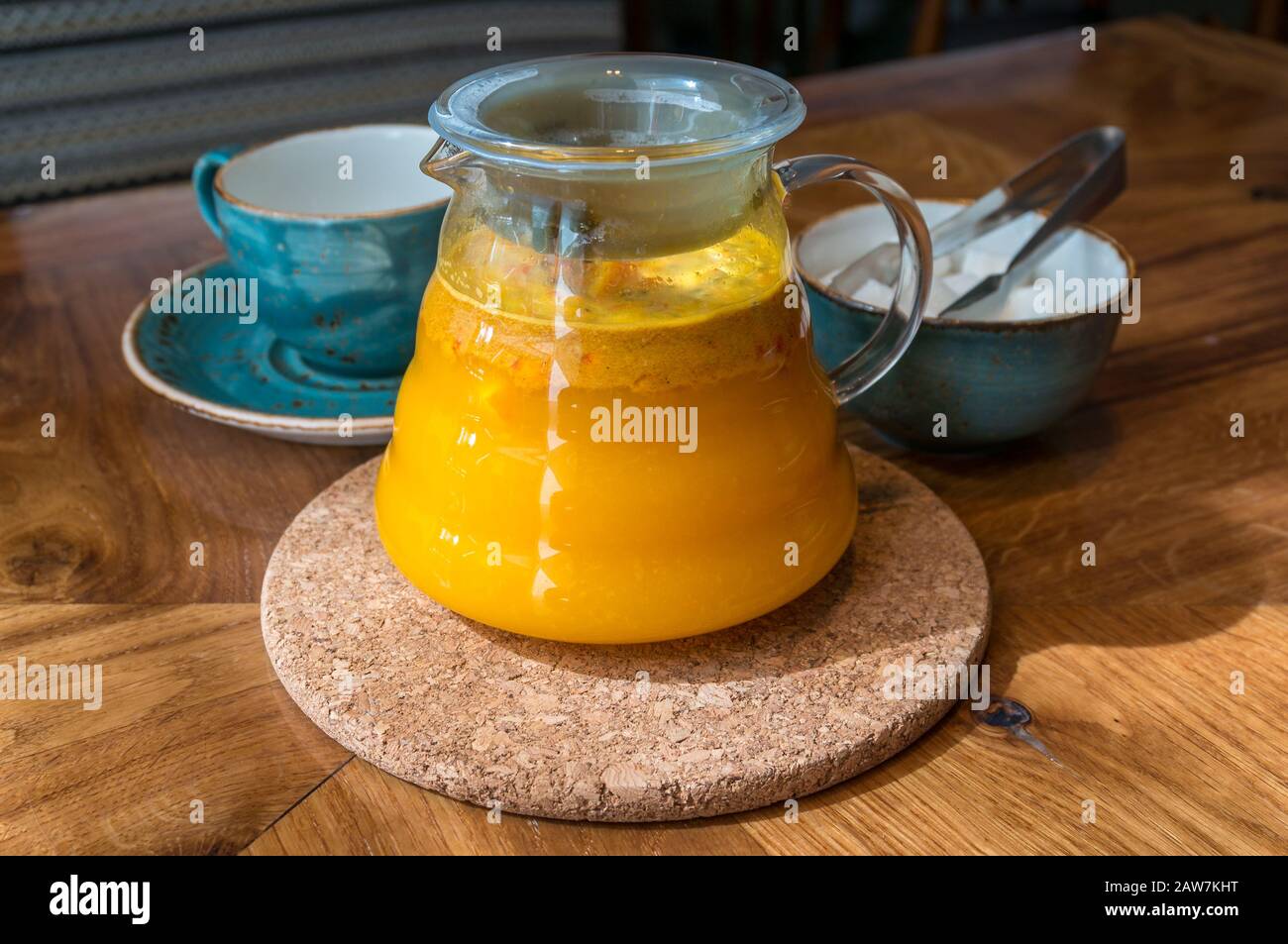 Meeresbuckdornbeere Tee-Infusion in Glas-Teekanne mit Teelbecher und Zuckerschüssel mit Zuckerzange. Kräutermedikament Tee auf dem Tisch Stockfoto