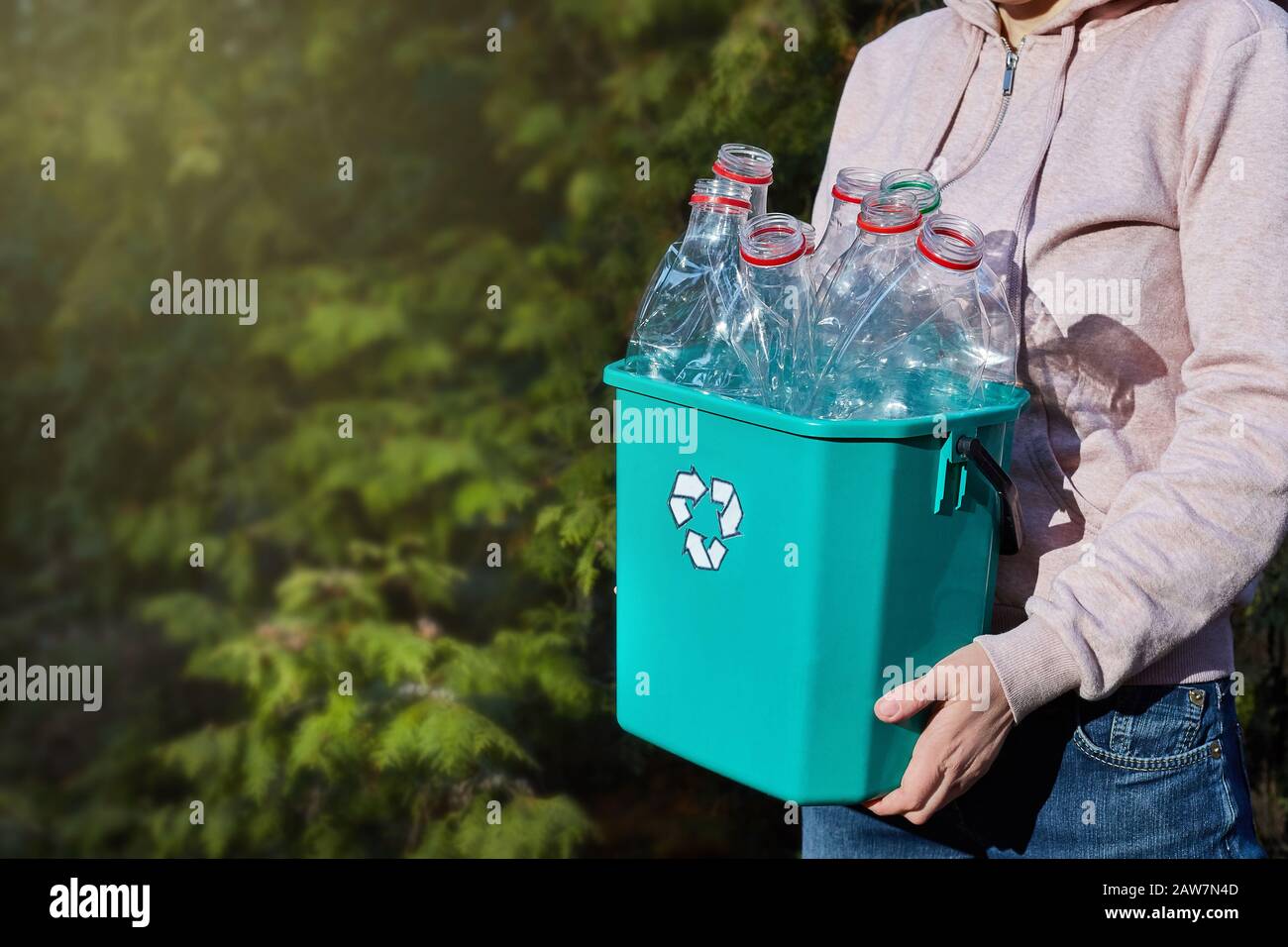 Nahaufnahme: Die Hände tragen eine Kunststoffbox zum Recycling. Umweltbewusstsein. Den Planeten retten. Copyspace. Stockfoto