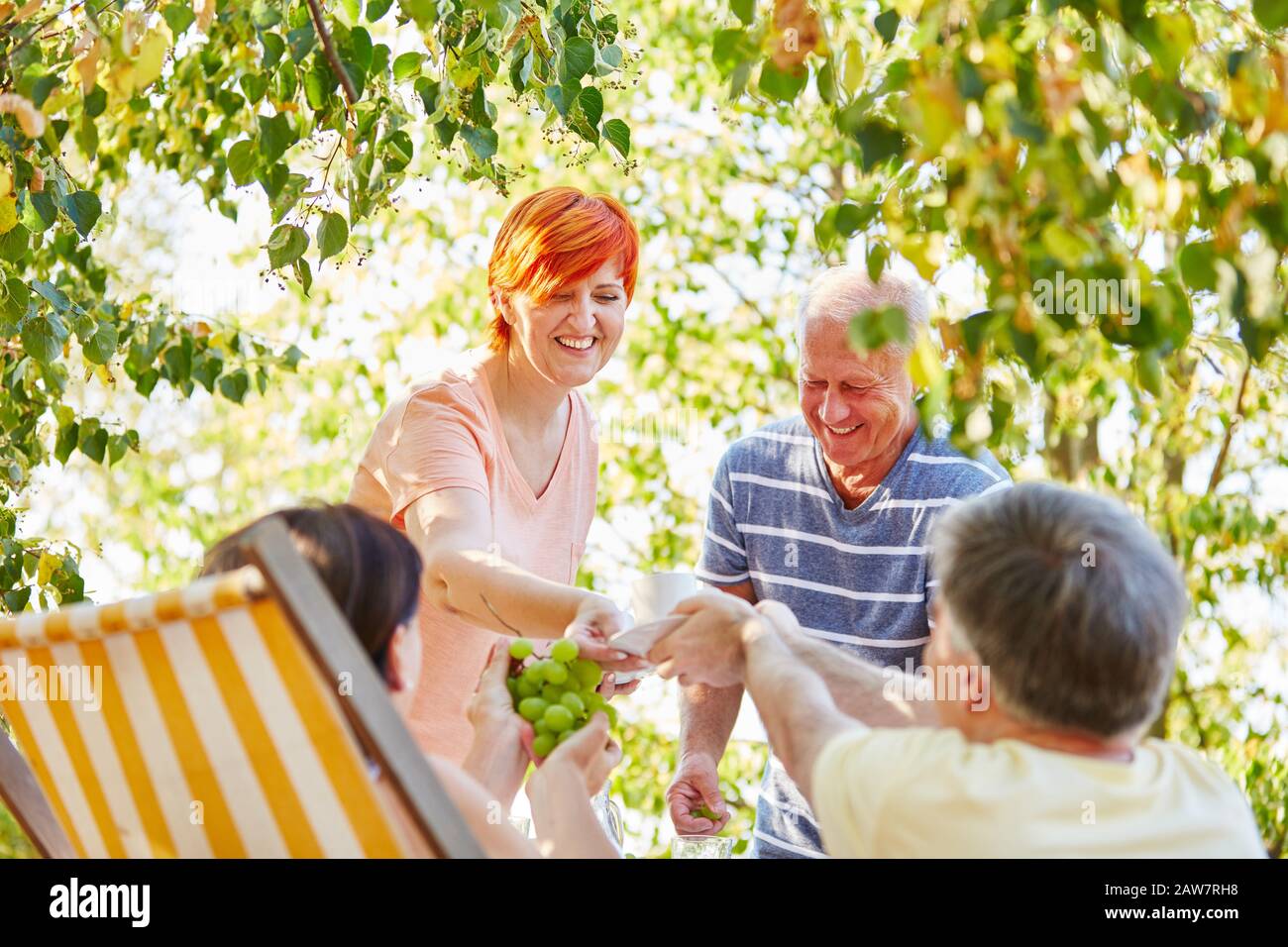 Fröhliche Gruppe von Senioren im Garten mit Kaffee und Obst Stockfoto