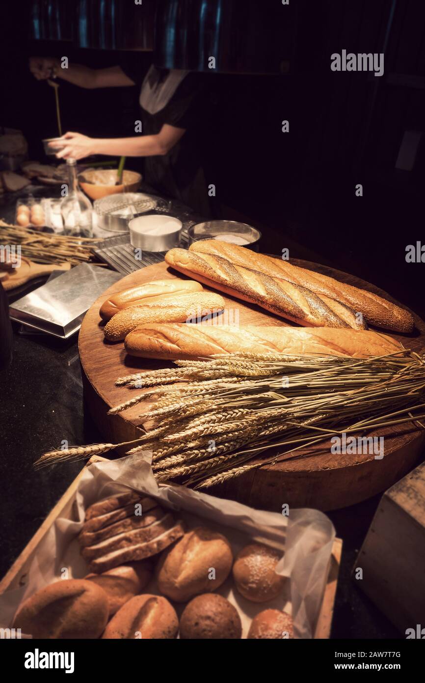 Frisch gebackenes traditionelles Brot auf Holztisch mit Backwaren für Frauen im Hintergrund Stockfoto