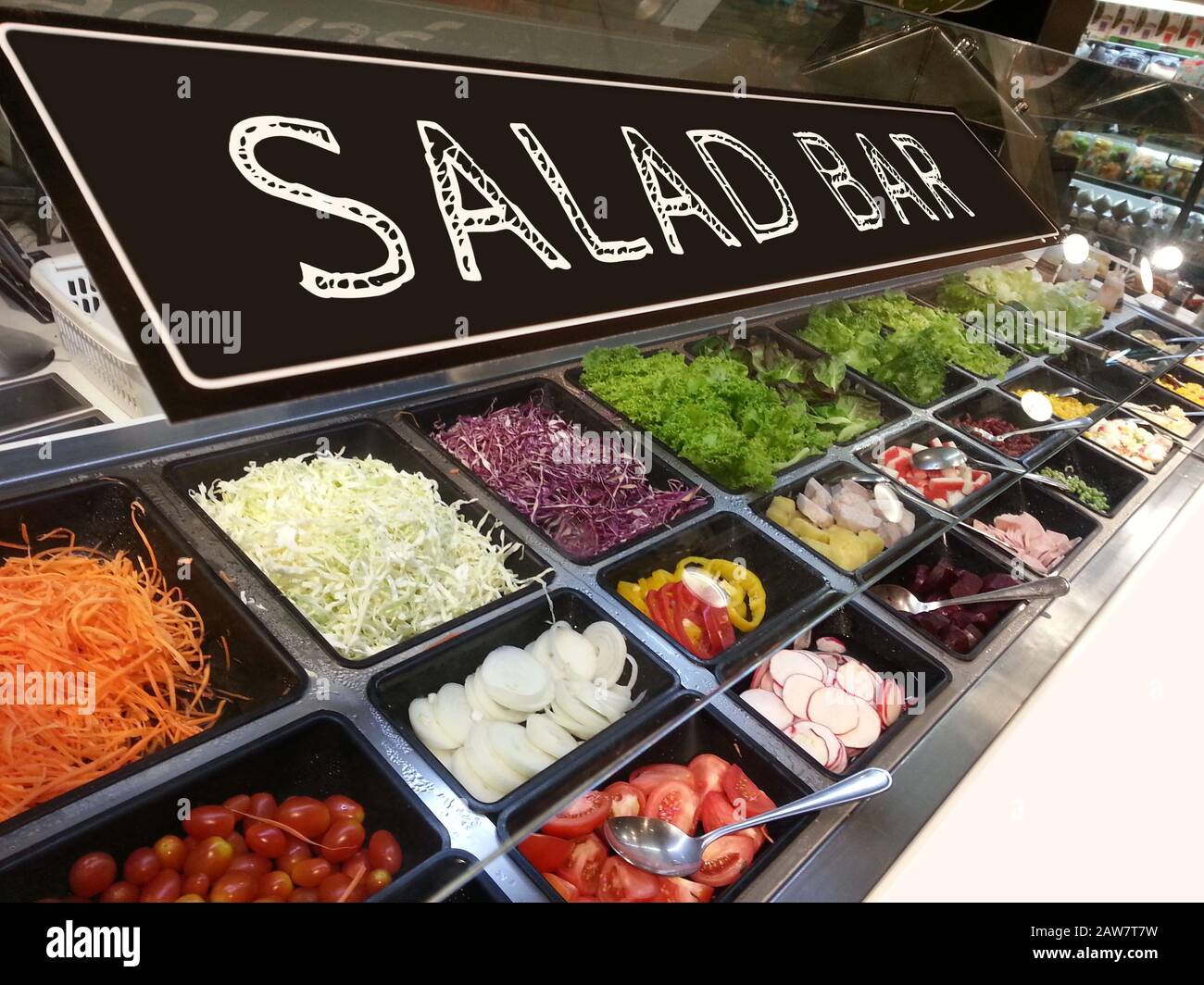 Verschiedene frische, bunte Gemüse- und Obstsorten an der Salatbar im Supermarkt mit einem Schild mit Salatbar Stockfoto