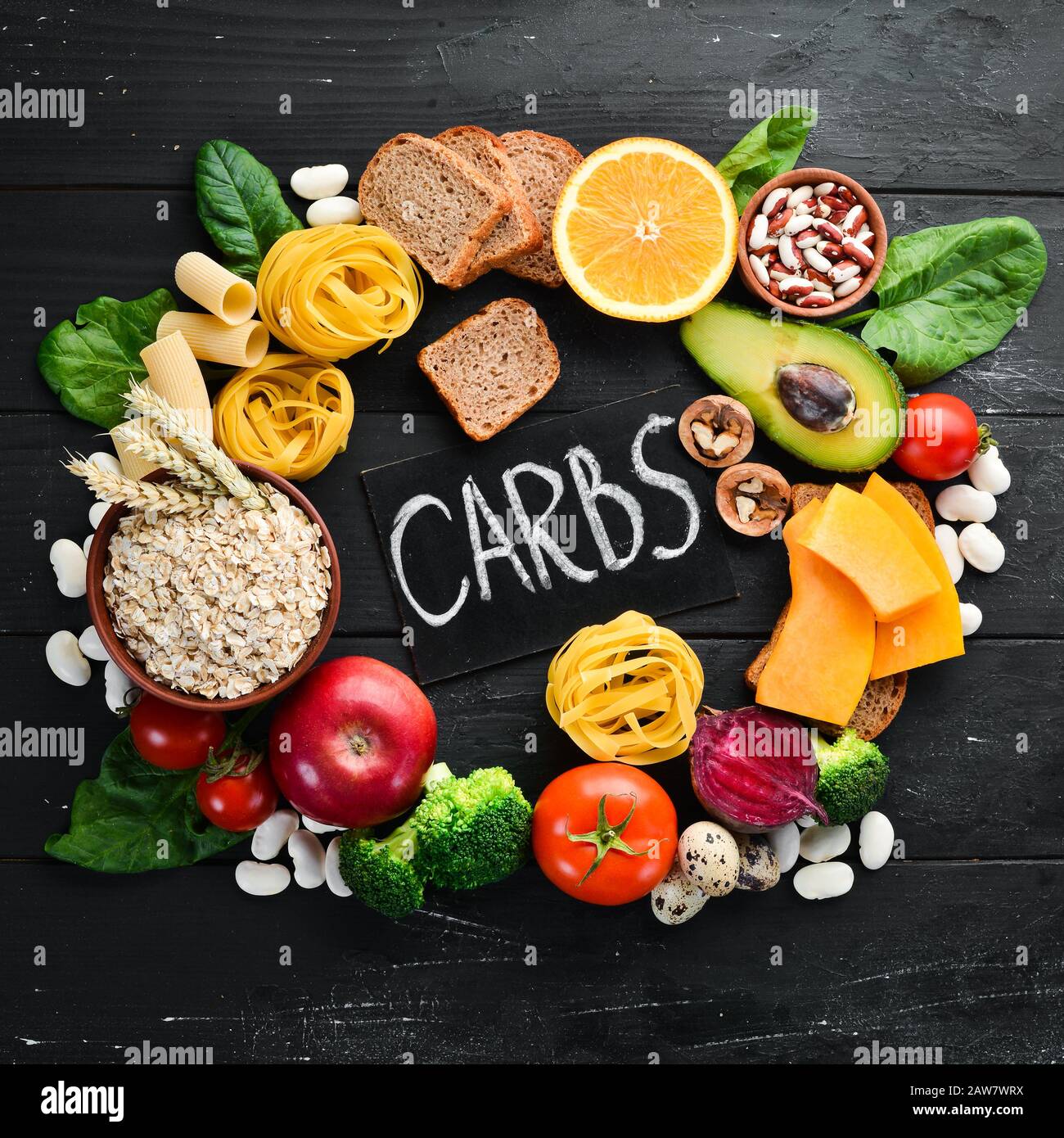 Kohlenhydratreiche Lebensmittel: Brot, Pasta, Avocado, Mehl, Kürbis, Brokkoli, Bohnen, Spinat. Das Konzept des gesunden Essens. Auf schwarzem Hintergrund. Stockfoto