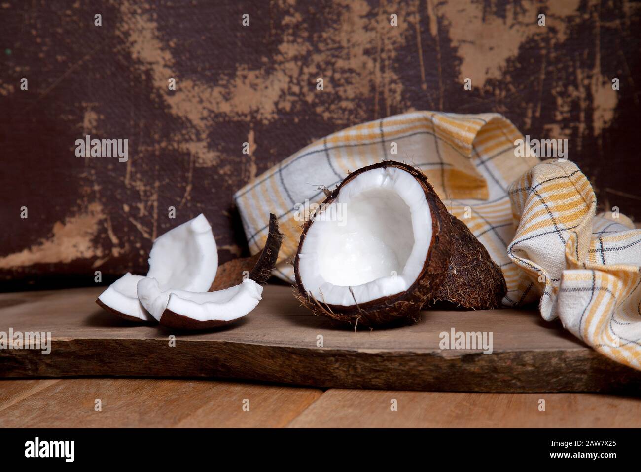Kokosnuss. Kokosnuss, Kokosflocken und kleine Stücke zerbroschter Nuss auf Holzgrund. Tropische Frucht-Kokosnuss in der Schale. Organisch gesund di Stockfoto