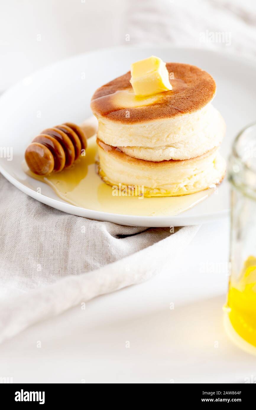 Flauschige japanische Soufflepancakes, Hotcakes mit Butter und Ahorn-Sirup oder Honigsaucen auf hellweißem Hintergrund. Trendige asiatische Küche zum Frühstück Stockfoto