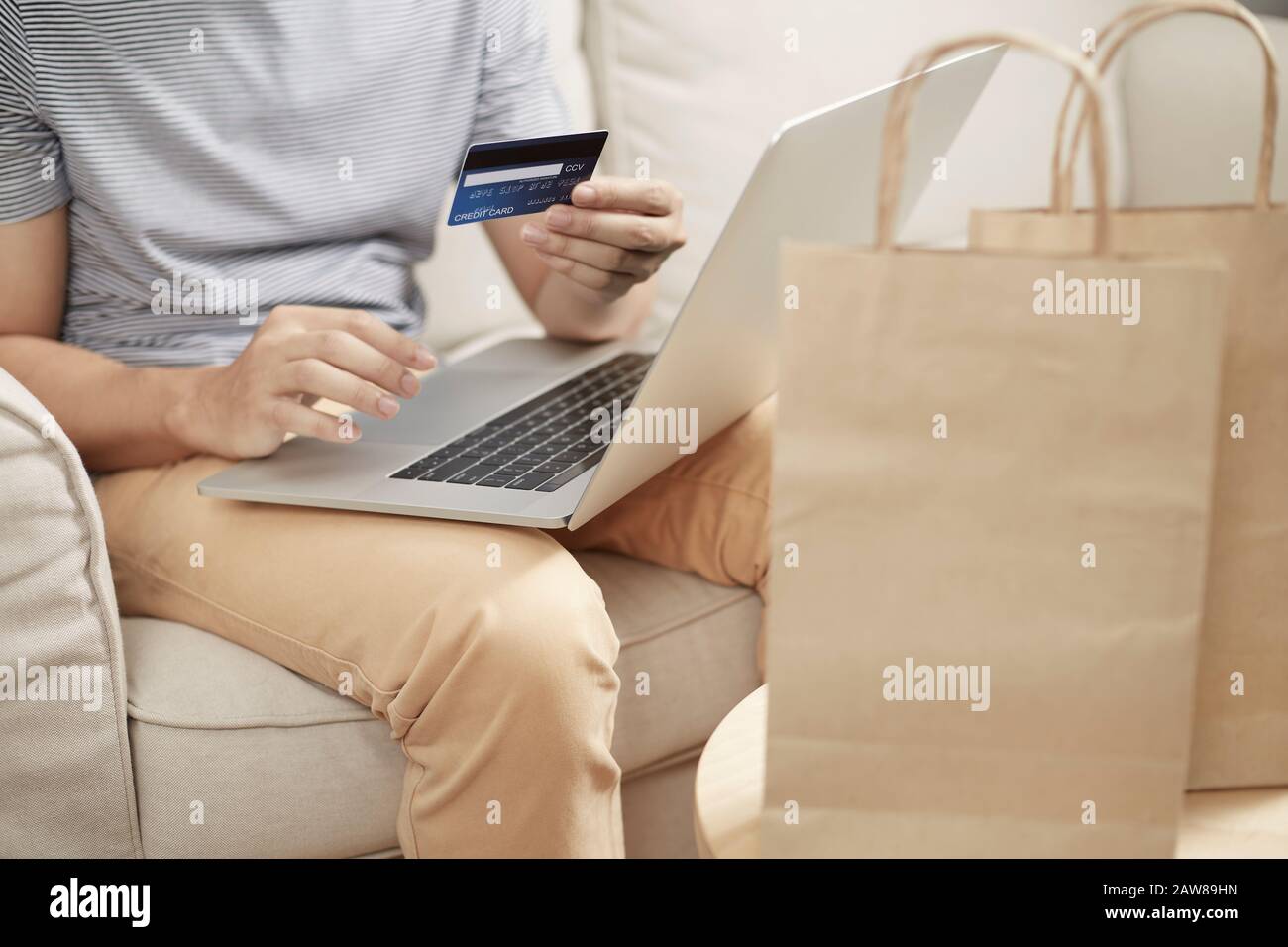 Mann Online-Shopping mit Laptop und Kreditkarte e Geldbörse und Papiertasche vorne keine Plastiktüte Stockfoto