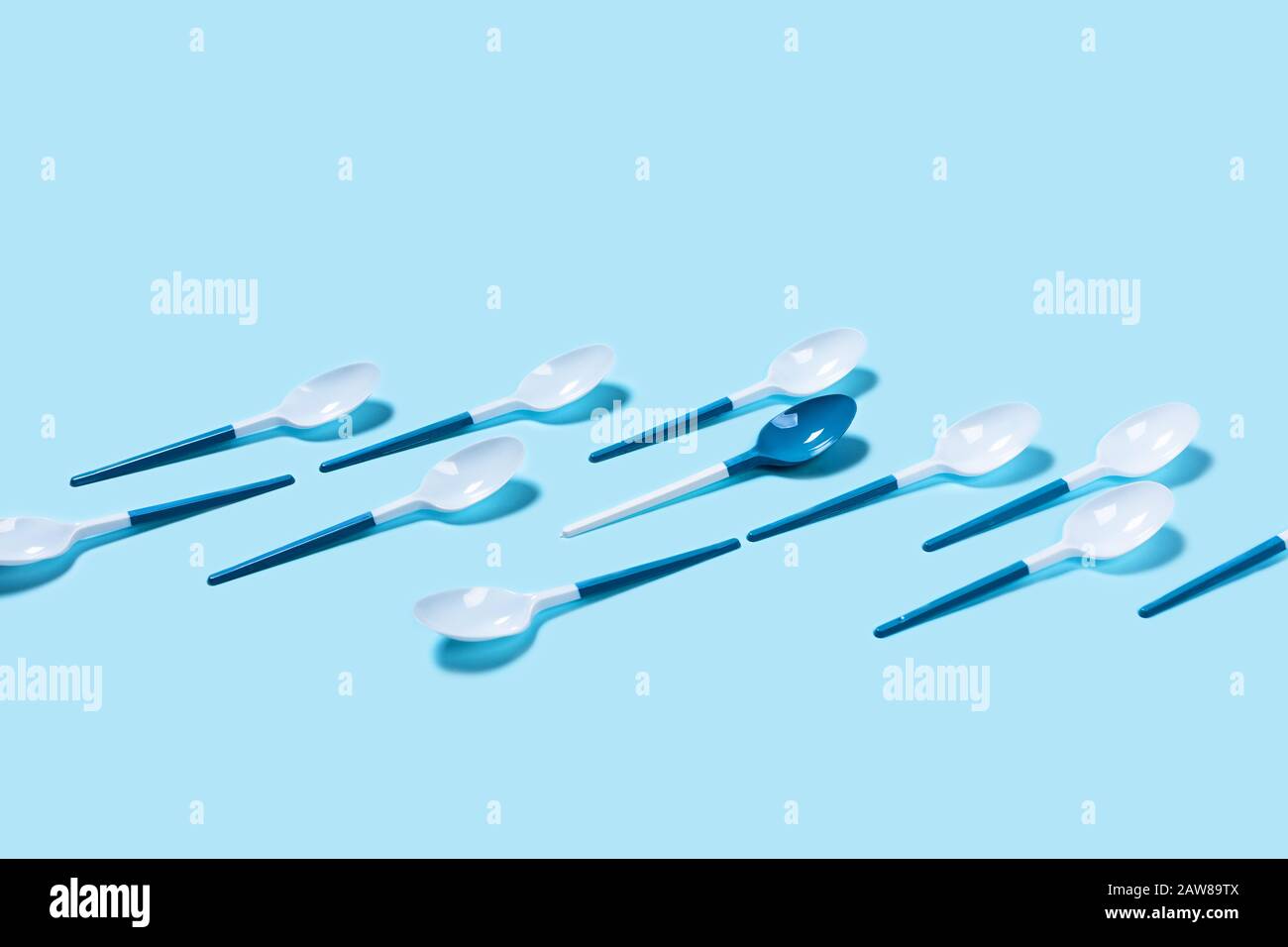 Abbildung der weißen und blauen Kunststofflöffel auf blauem Hintergrund. Flaches Layout, Draufsicht, Kopierbereich. Stockfoto