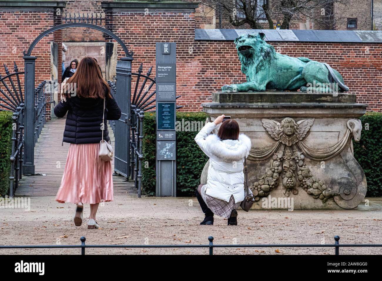 Hvilende Loever, Einer Von Zwei Ruhenden Löwen. Bronzeplastiken im Königsgarten auf Schloss Rosenborg, Kopenhagen, Dänemark. Frauen Tourist fotografieren Stockfoto