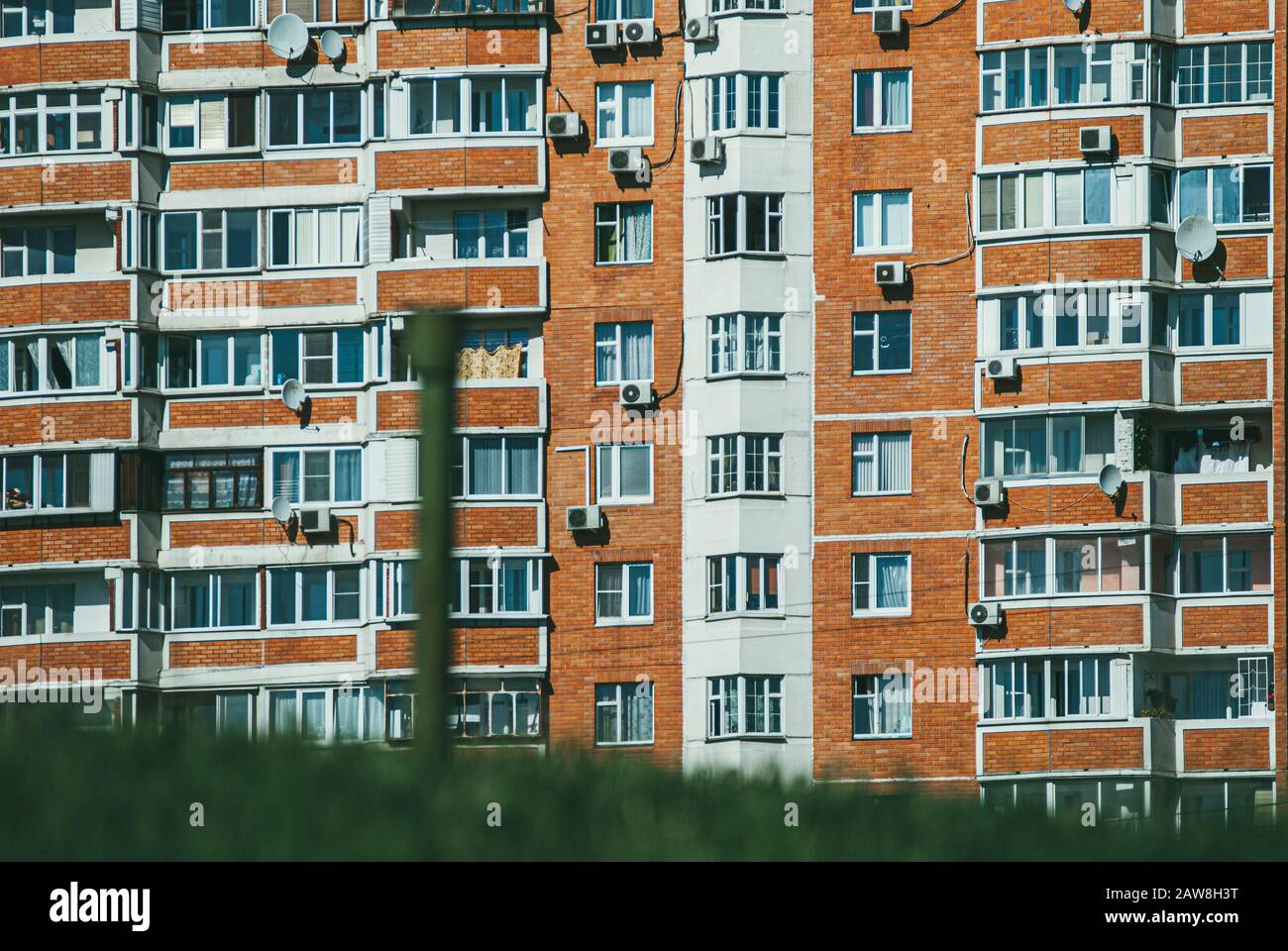 Modernes neues Mehrfamilien-Wohnhaus mit grünem Gras im Vordergrund, das Konzept des neuen Lebens und Umzugsens. Selektives Fokusmakro mit aufgenommen Stockfoto