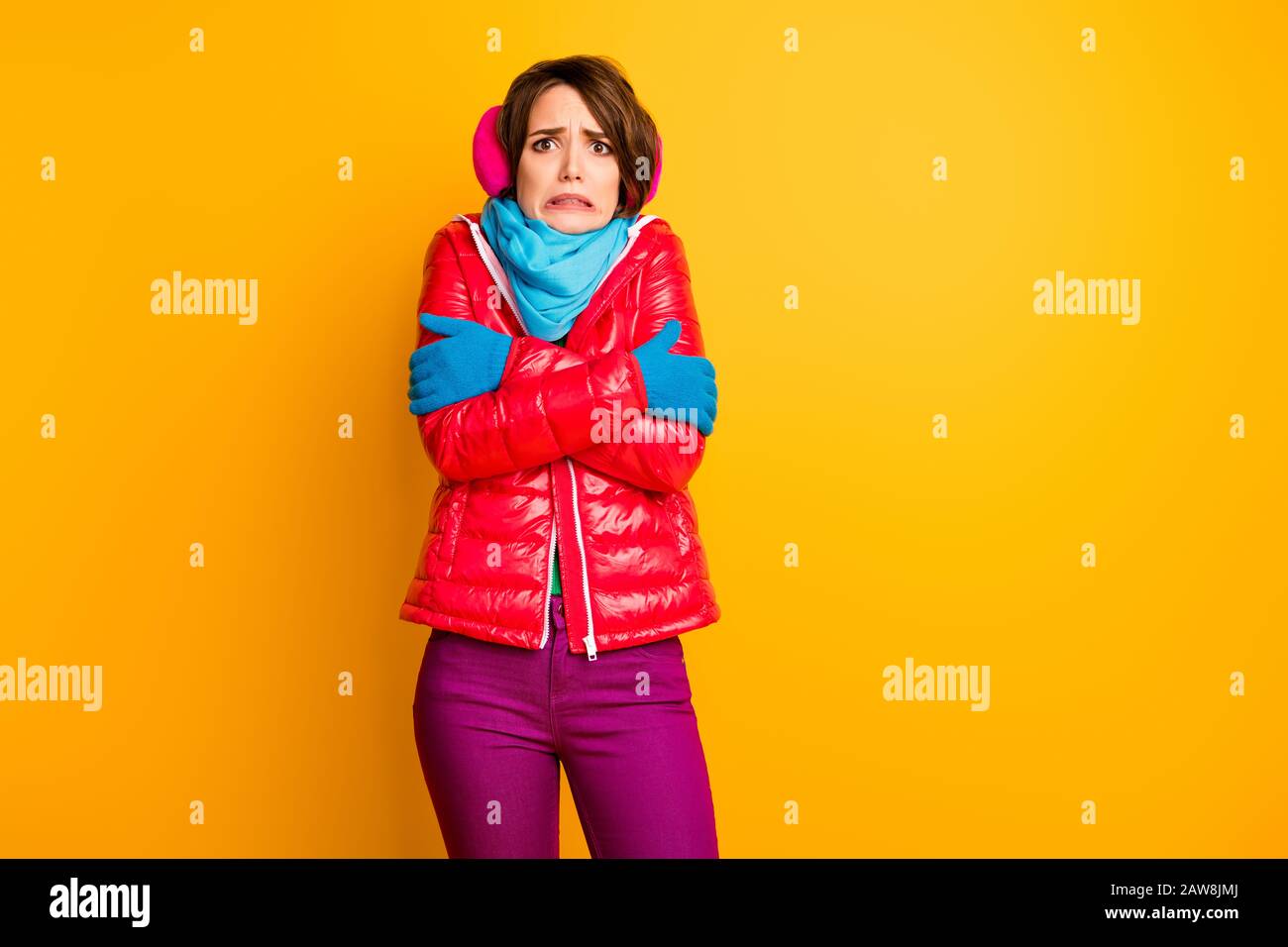 Foto von lustiger Reisender Lady erwartet nicht Frosty Wetter Schütteln Umarmung selbst tragen stylische Freizeit kurz rot Übermantel blau Schal Handschuhe Ohrwärmer Hosen Stockfoto