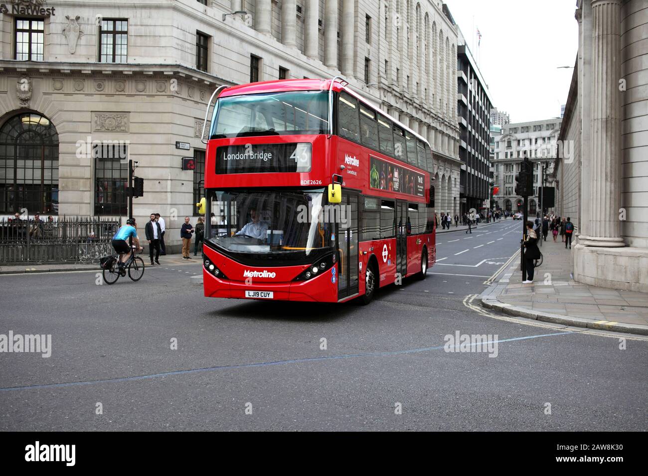 Ein elektrischer (batteriebetriebener) Doppeldeckerbus, der einen Radfahrer an der Bank in der City of London vorbeiführt. Und fast kein Verkehr! Stockfoto