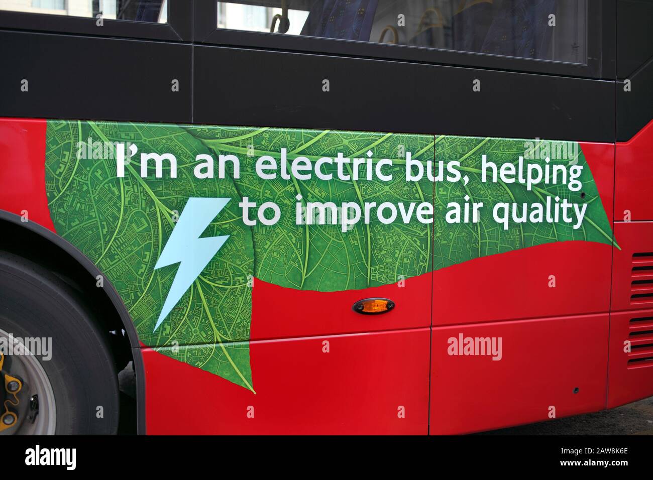 Werbung an der Seite eines elektrischen Busses in London, der seine Rolle bei der Verbesserung der Luftqualität bekannt gibt. Lancaster Place, London. Stockfoto