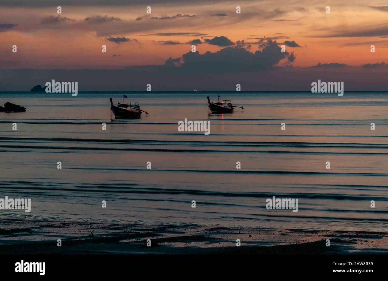 Glorreicher tropischer Sonnenuntergang am Strand von Ao Nang, Provinz Krabi, Thailand, mit zwei langen Schwanzbooten Stockfoto