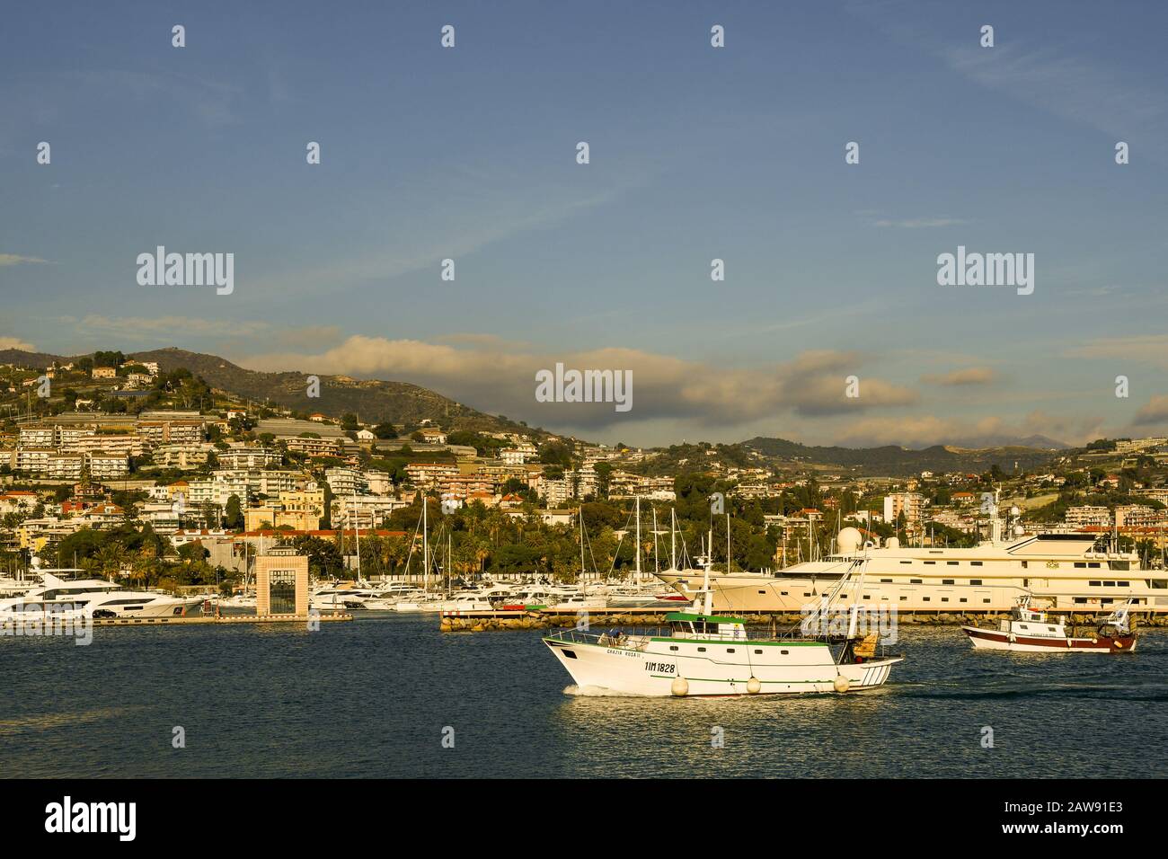 Fischerboote, die in den Hafen einlaufen, sowie Luxusyachten und Segelboote, die im Touristenhafen Porto Sole der Küstenstadt Sanremo, Ligurien, Italien, vergraben sind Stockfoto