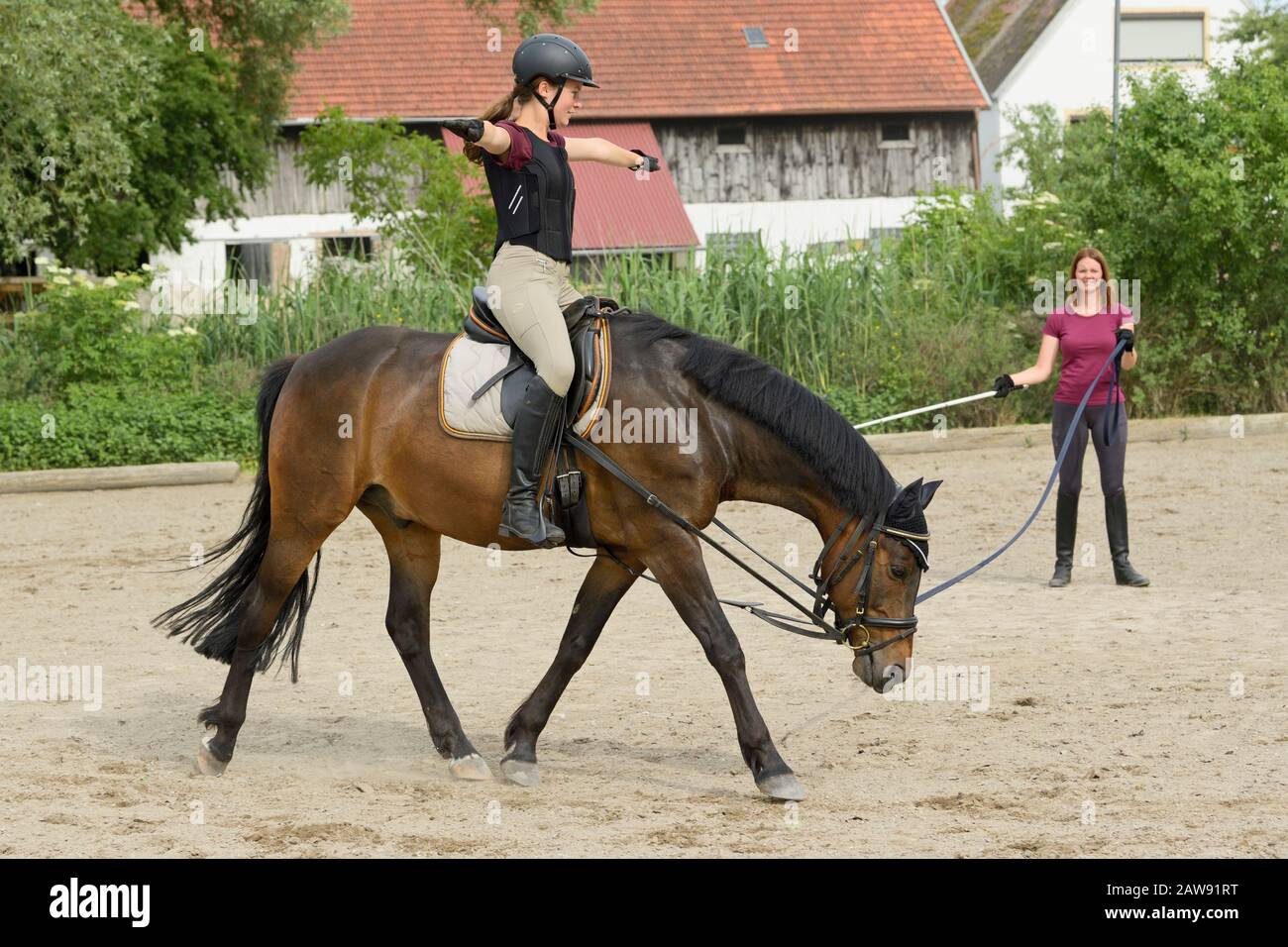Ausfallstunde, Mädchen mit Helm und Rückenprotektor auf deutschem Pony reiten Stockfoto