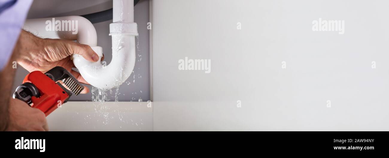 Die männlichen Klempner Hand Instandsetzung Waschbecken Leckage mit verstellbarer Schraubenschlüssel Stockfoto
