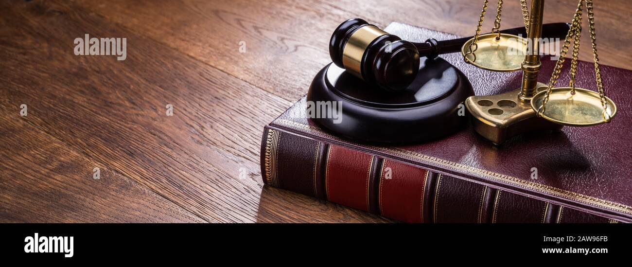 Holz- Hammer mit goldenen Skala in der Nähe von Buch am Tisch Stockfoto