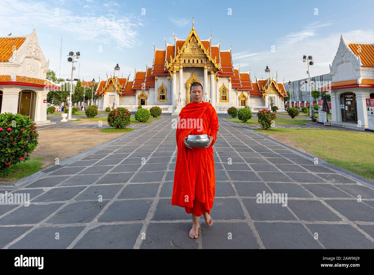 Mönch hält seine Schale, um Nahrung und Opfergaben am Tor des Marmortempels zu sammeln, der als Wat Benchamabopit Dusitvanaram in Bangkok, Thailand, bekannt ist Stockfoto