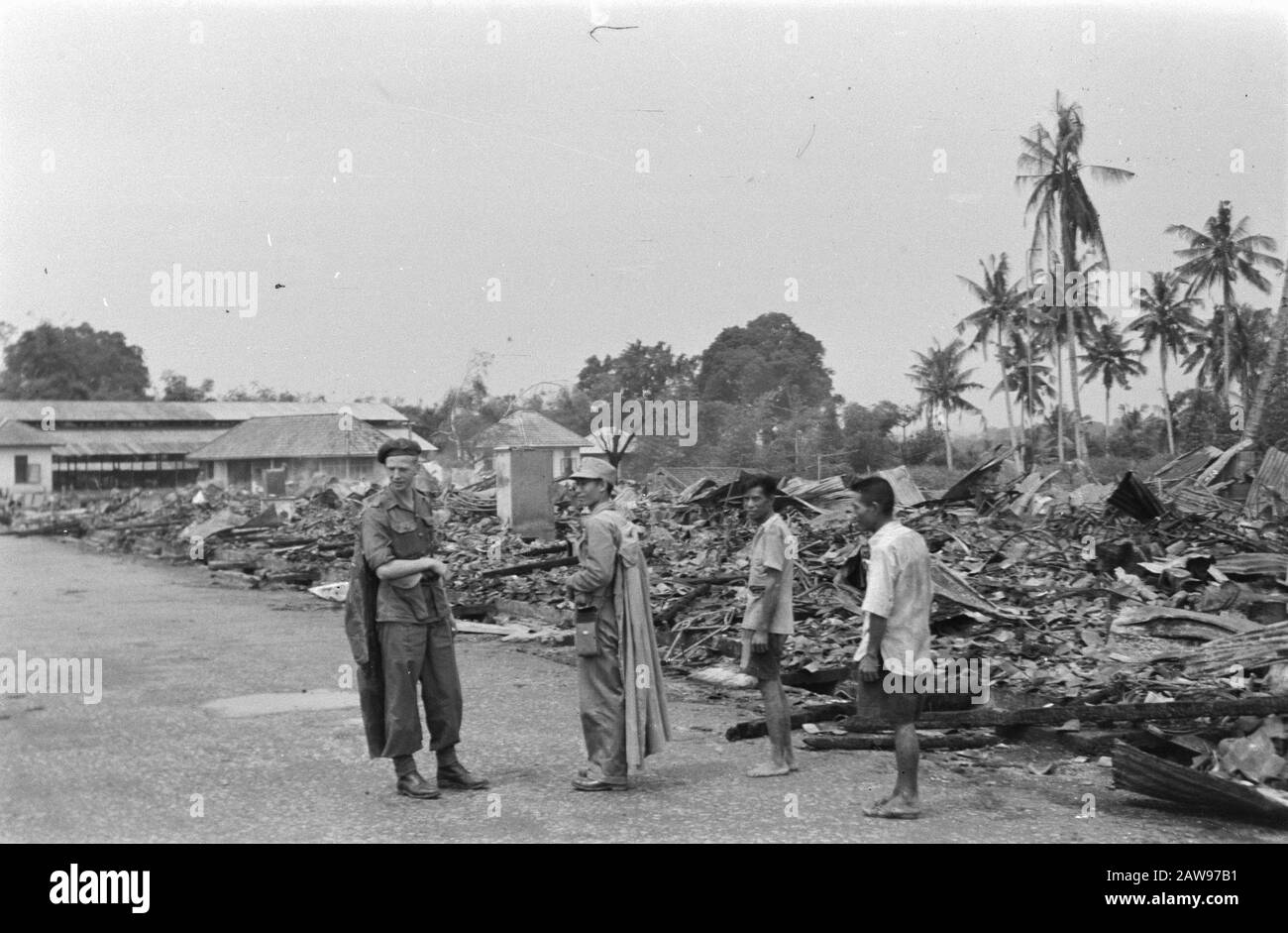 Bericht Deli Toea niederländischer Soldat steht unter den Ruinen. Neben ihm ein japanischer Gefangener mit kap, flankiert von zwei Männern in Zivildatum (?): Juli 1947 Ort: Indonesien Niederländisches Ostindien Stockfoto