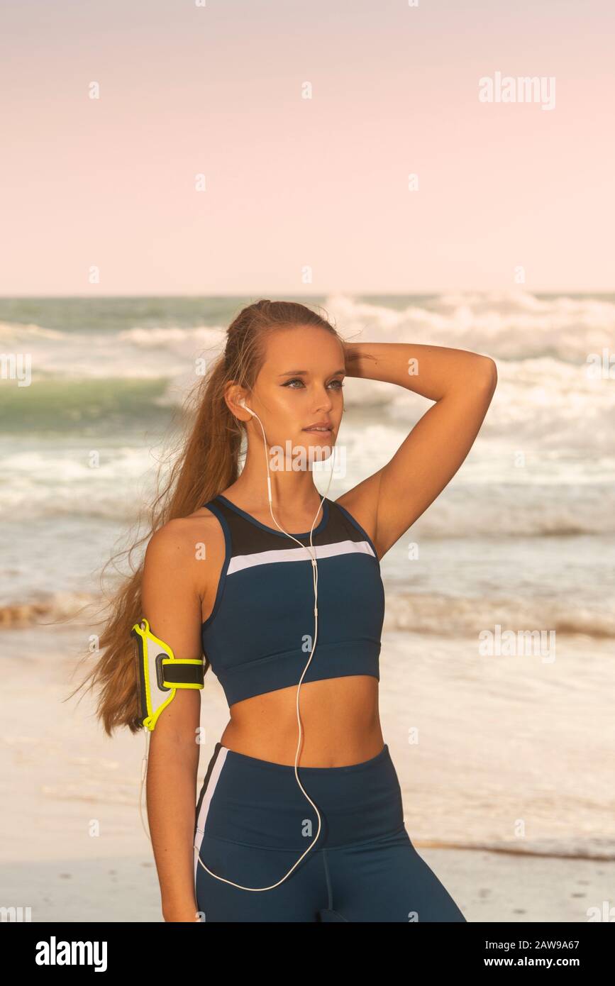 Fit für sportliche Frau mit Sportswear und einem Armband für Smartphone, am Meer stehend Stockfoto