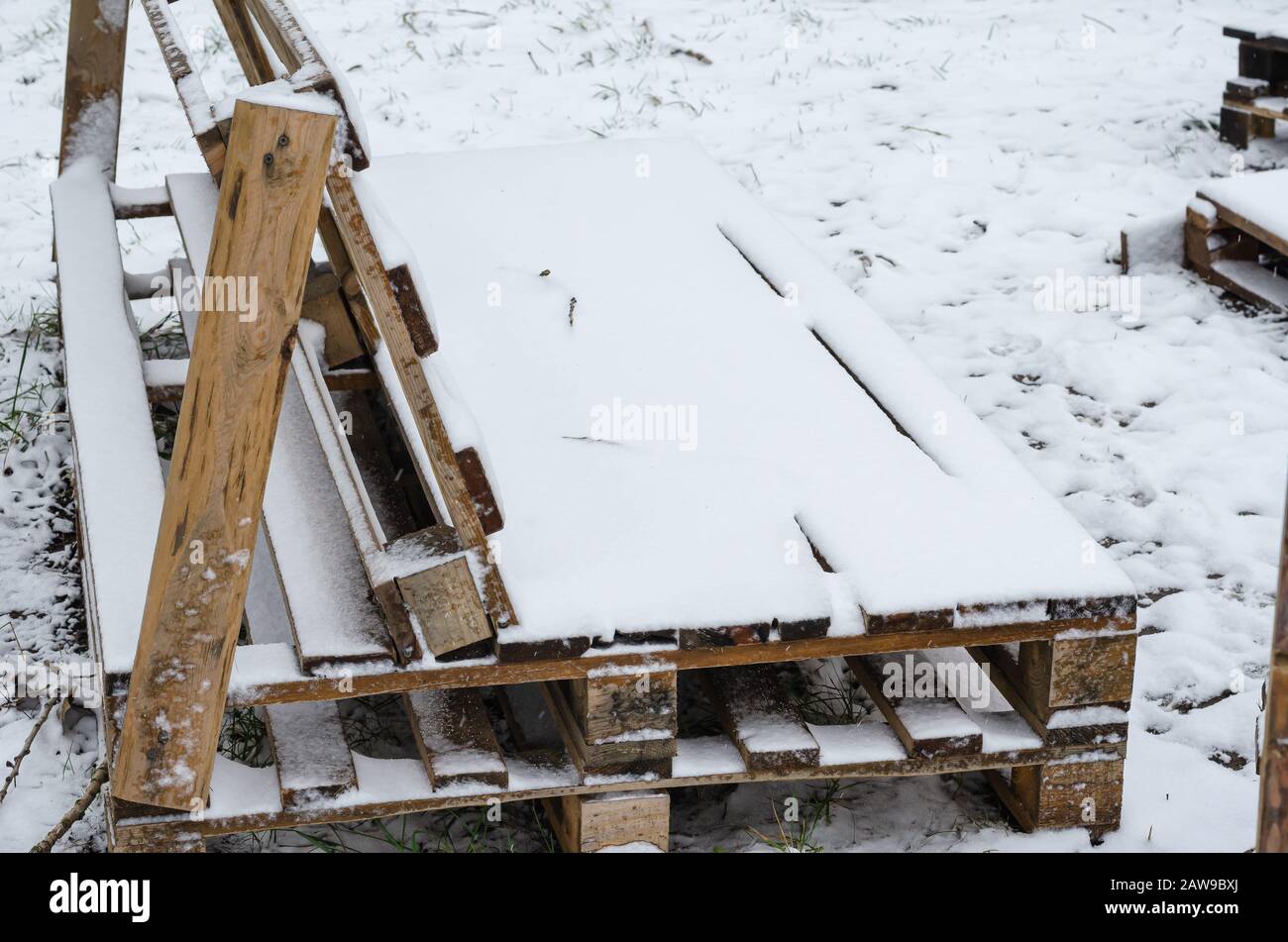 Seitenansicht einer leeren Bank mit Schnee. Kalter Wintertag mit fliegenden Schneeflocken. Selektiver Fokus. Ohne Menschen. Stadtleben Stockfoto