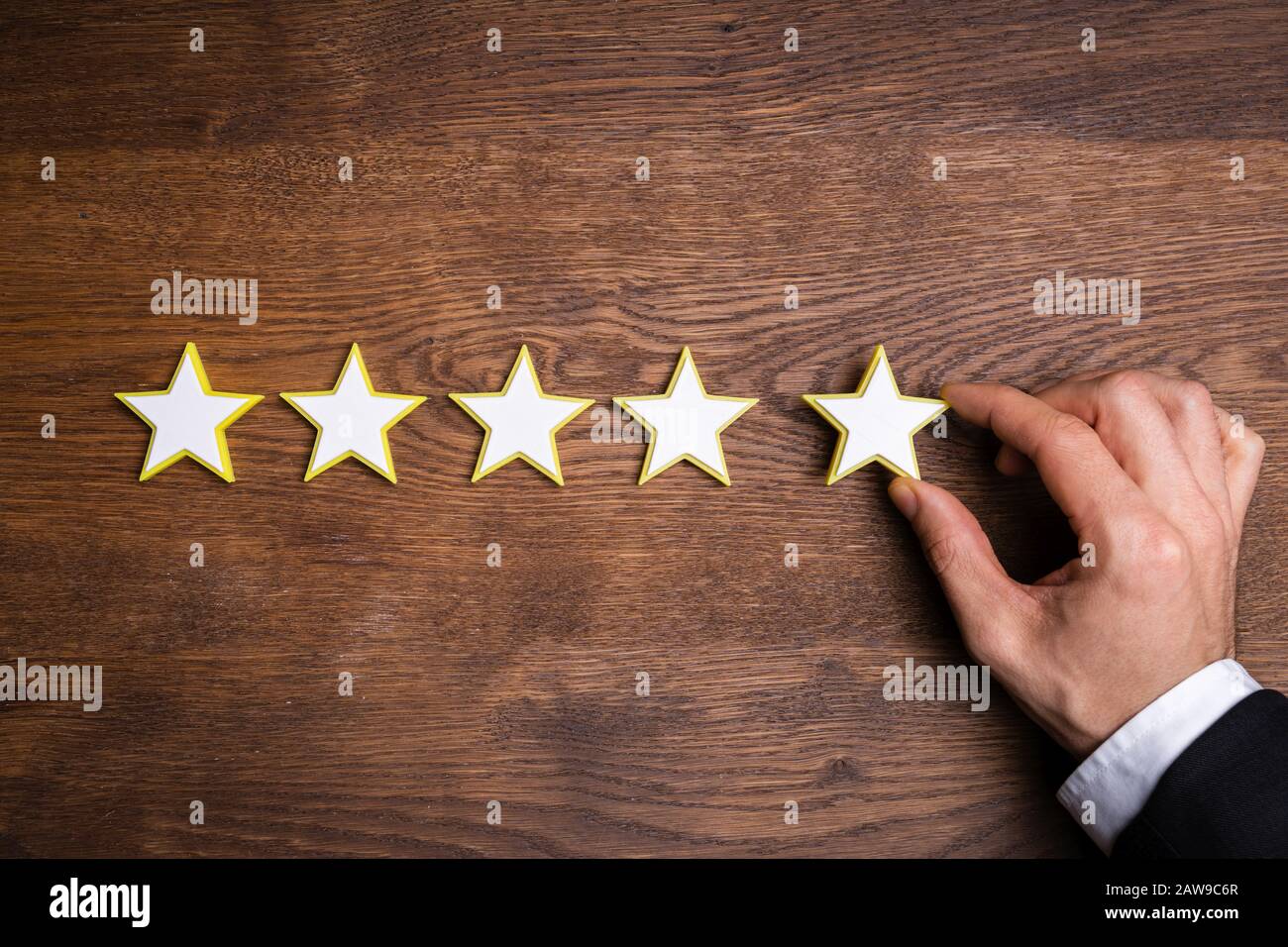 Die Hand der Person, Die Das Symbol Für Die Bewertung Von Fünf Sternen Am Schreibtisch bildet Stockfoto