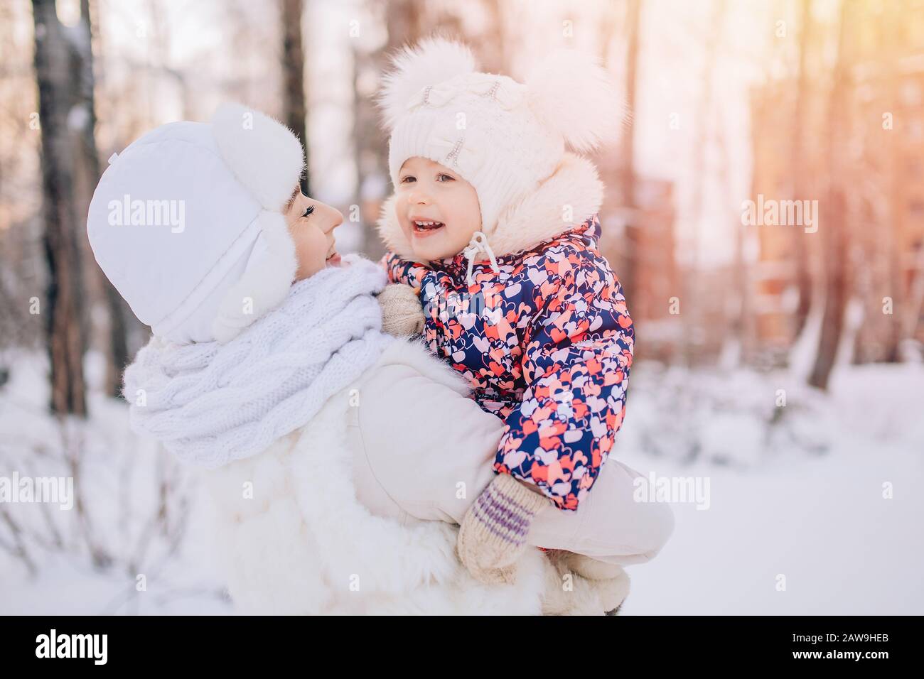 Mutter und kleine Tochter auf einem Spaziergang im Winterschnee im Park, lächelnd und lustig. Konzept Liebe Familie. Stockfoto