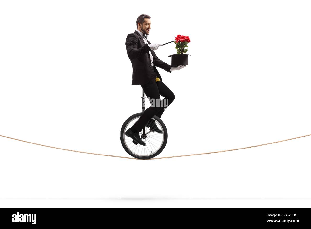 Zauberer mit einem Zauberstab, der auf einem Einrad reitet und einen Trick mit roten Rosen und einem Hut ausführt, der auf weißem Hintergrund isoliert ist Stockfoto