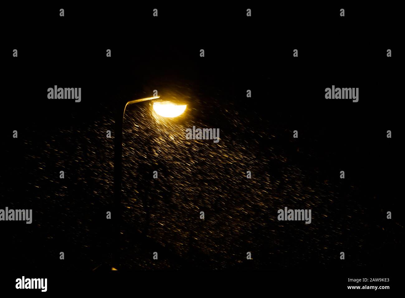 Langsame Verschlusszeit mit starkem Schneesturm und starkem Wind in Licht eines Straßenlampenpostens. Stockfoto