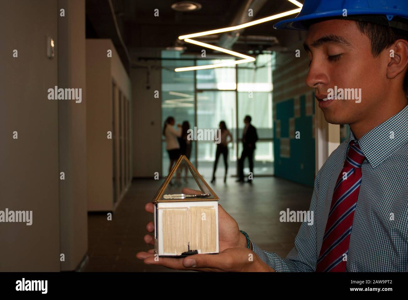 Architekt hält in seinen Händen den konzeptuellen Mock-up, der seinen Kunden auf symbolische Weise liefert, um eine Benutzererfahrung mit seiner Arbeit zu realisieren Stockfoto