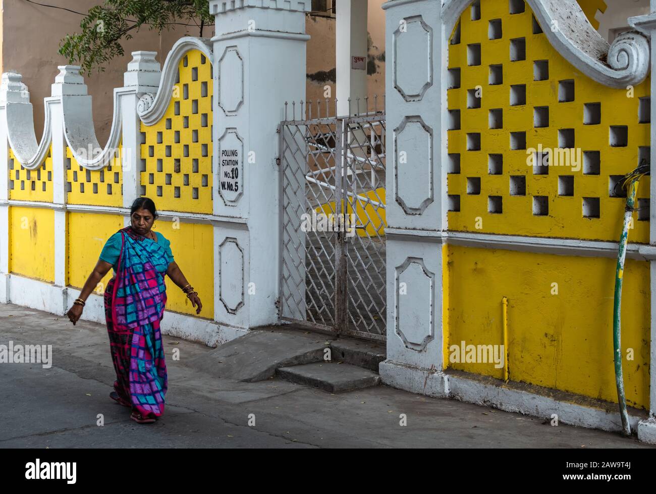 DIU, Indien - Dezember 2018: Eine Frau geht an den gelben Wänden eines Hauses auf den Straßen von Diu vorbei. Stockfoto
