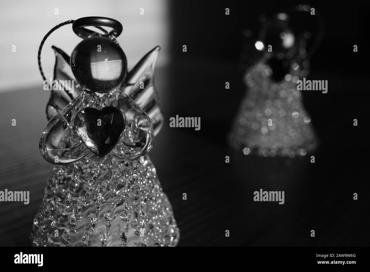 Zwei kleine Engelstatuen auf dem Tisch. Hell mit dunkel. Schwarzweiß-Foto Stockfoto