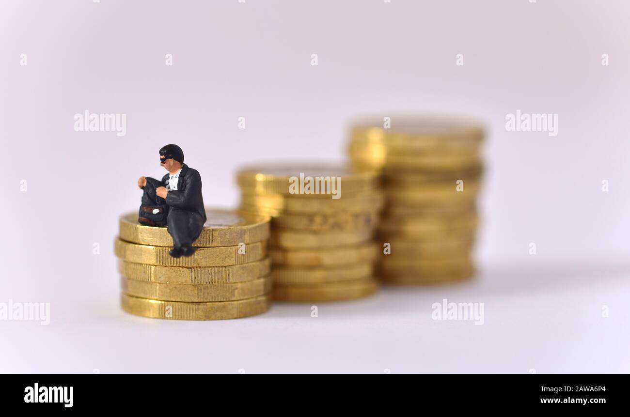 Modell des Mannes, der eine Sonnenbrille trägt und in der Jackentasche schaut, während er auf einem Stapel von Münzen mit einem Pfund sitzt. Stockfoto