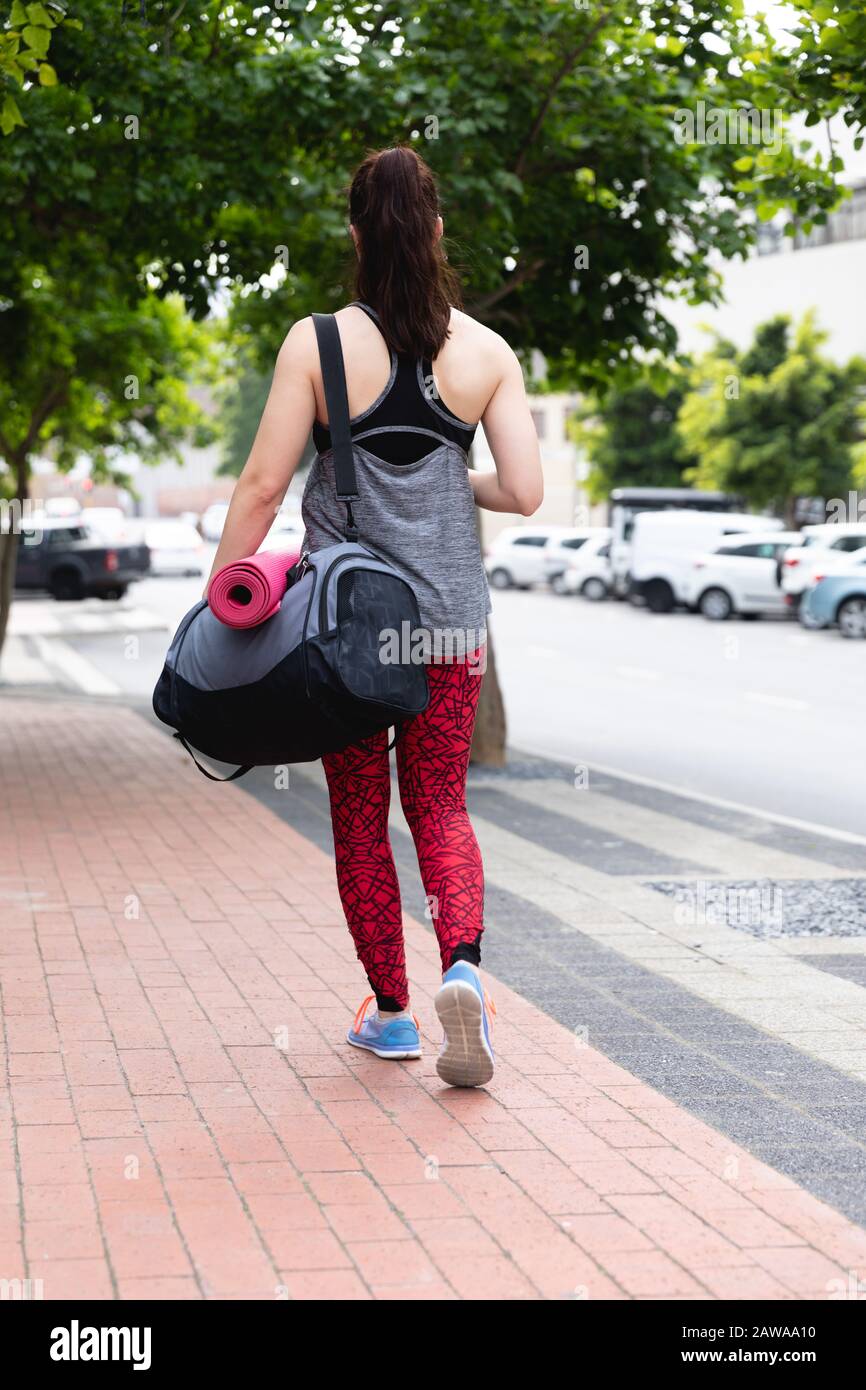 Kaukasische Frau, die mit einer Yogamatte spazieren geht Stockfoto