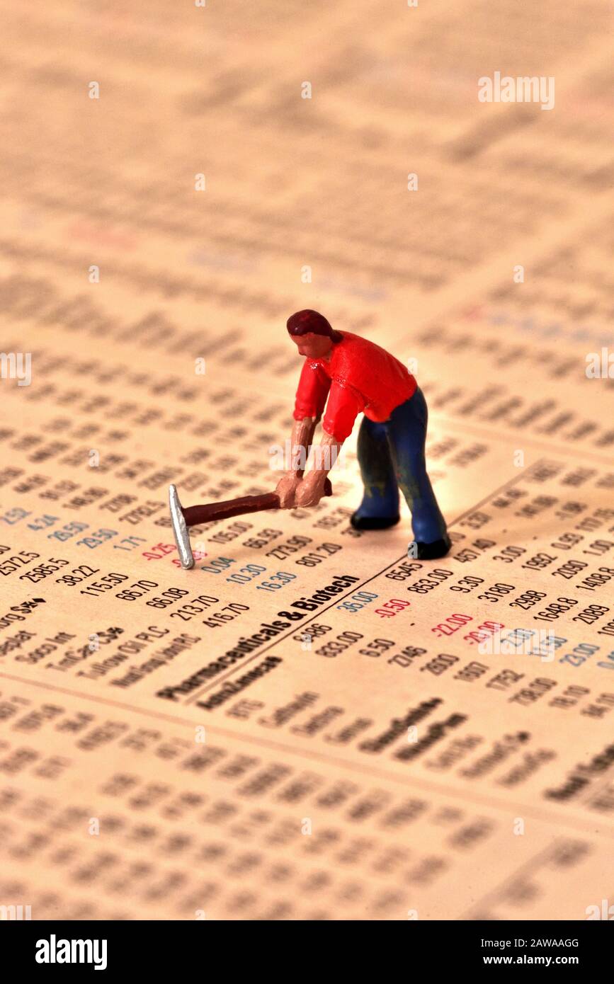 Modell des Mannes in rotem Hemd mit wählenden Taxen, auf Aktien und Aktien Seite der Finanzzeitung. Stockfoto