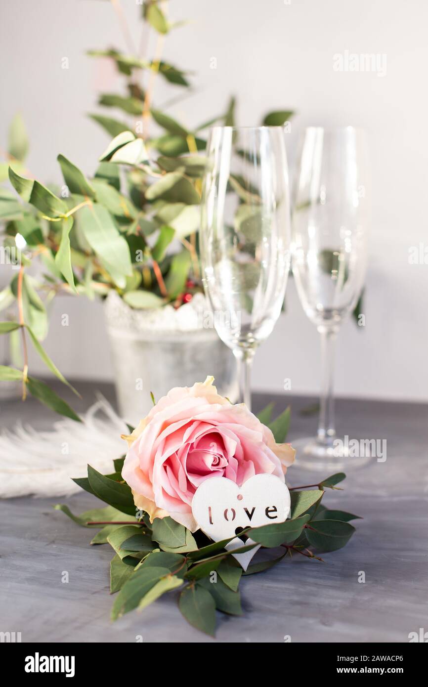 Komposition mit Glas für Champagner. Blumen und Herzen auf grauem Betonhintergrund Stockfoto