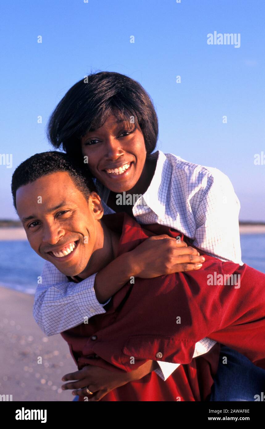 Junge afroamerikanische Paare täuschen sich herum und lieben sich auf einem Strandurlaub Stockfoto