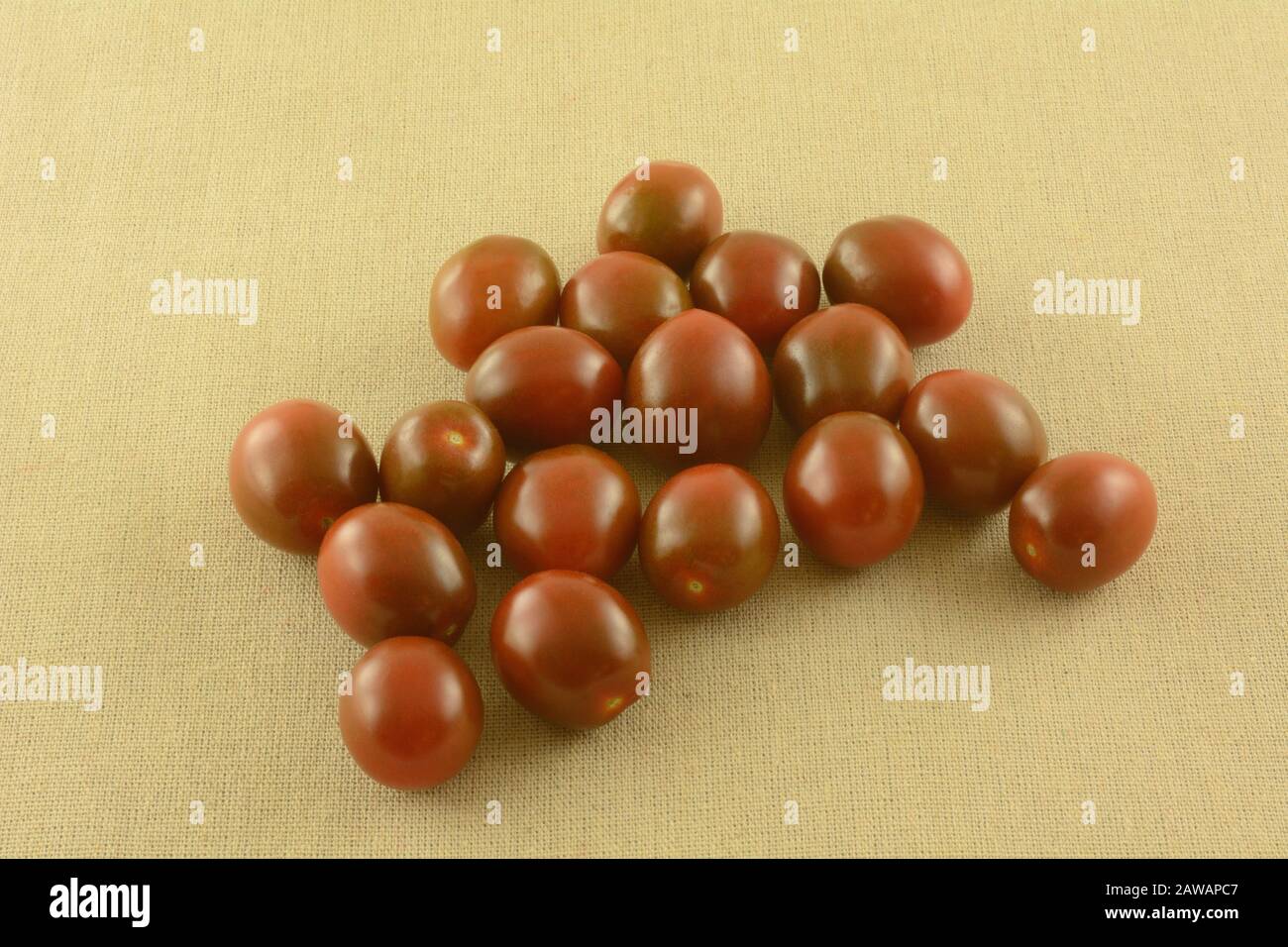Haufen roher, kleiner, brauner Tomaten auf tanneigem Tischtuch Stockfoto