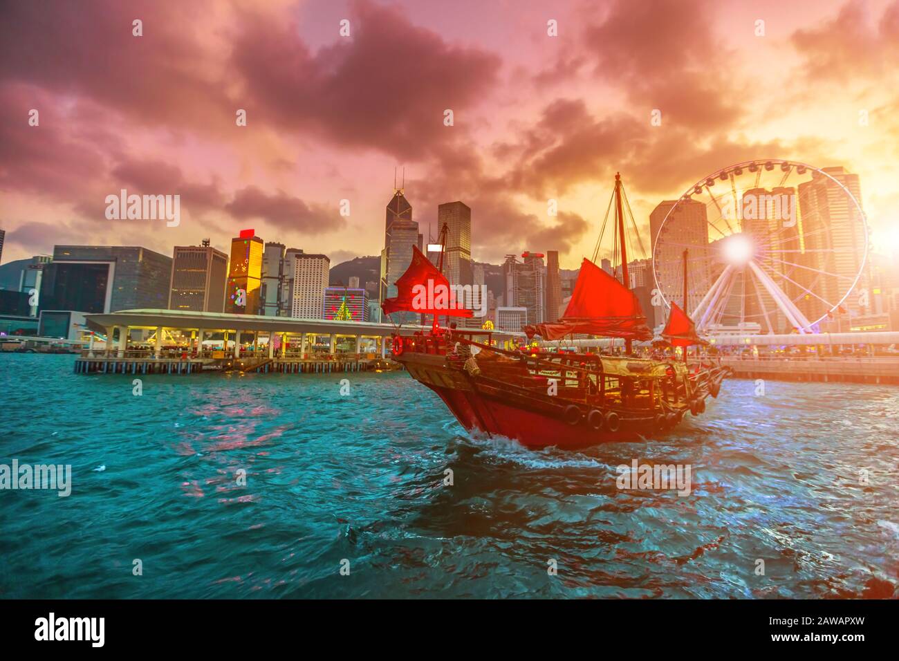 Trödelboot bei Sonnenuntergang mit Wolkenkratzern und Gebäude der Skyline der Stadt Hongkong in China. Stockfoto