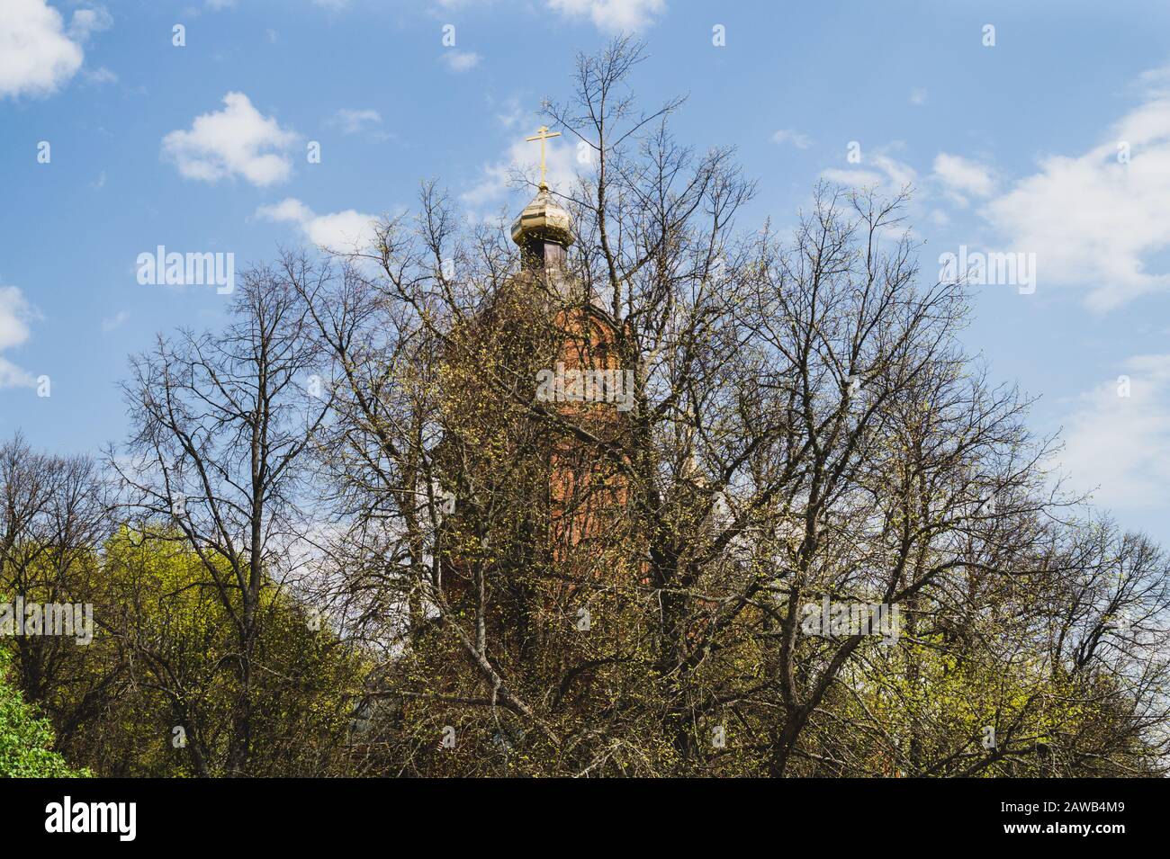 Schöner alter Kirchturm mit dem Kreuz auf dem Hügel. Kirche im Wald Stockfoto