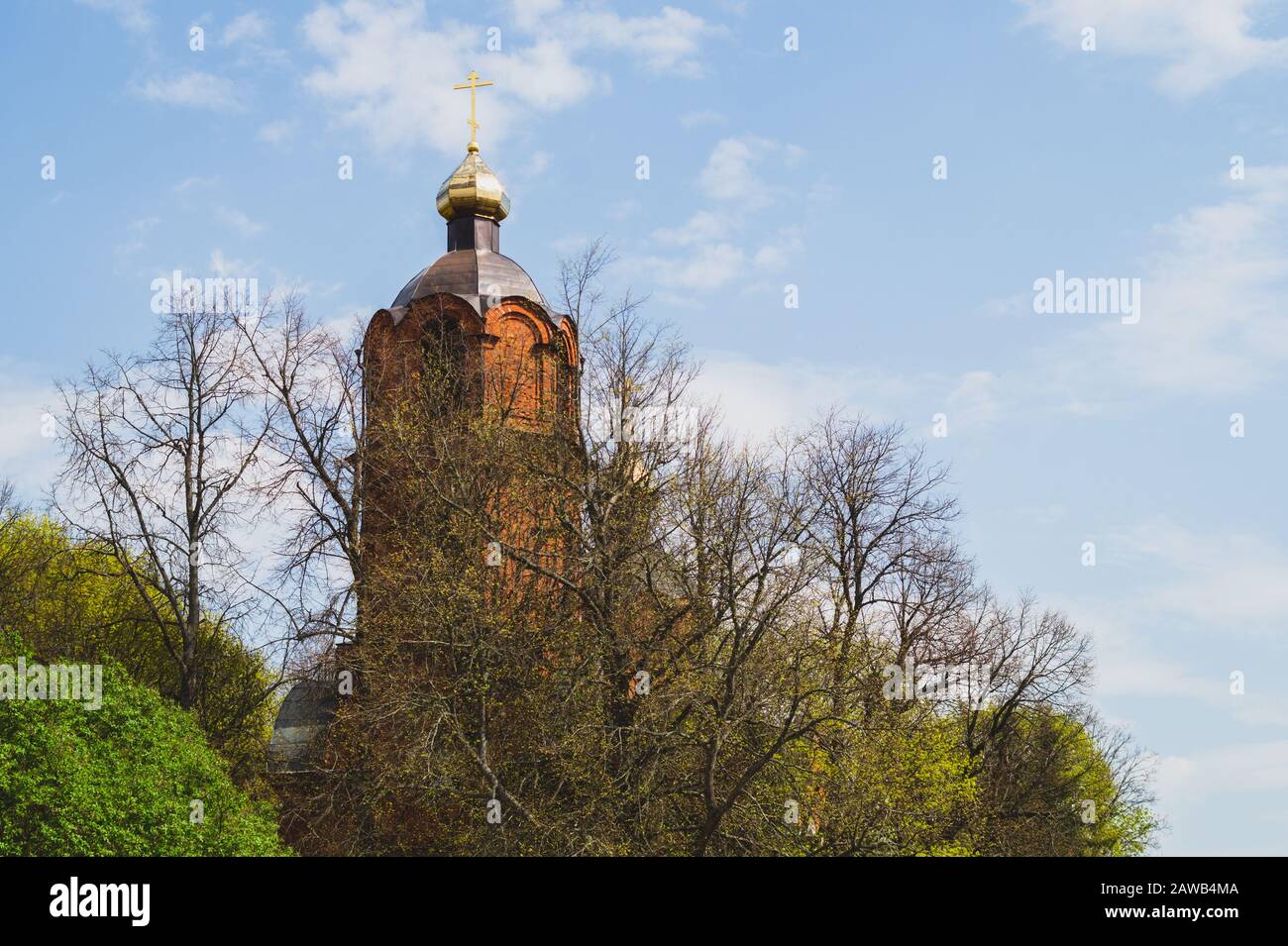 Schöner alter Kirchturm mit dem Kreuz auf dem Hügel. Kirche im Wald Stockfoto