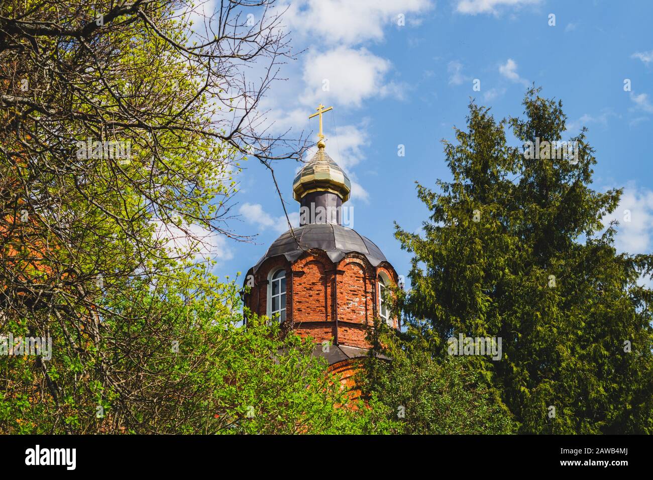 Schöner alter Kirchturm mit dem Kreuz auf dem Hügel. Kirche im Wald Stockfoto
