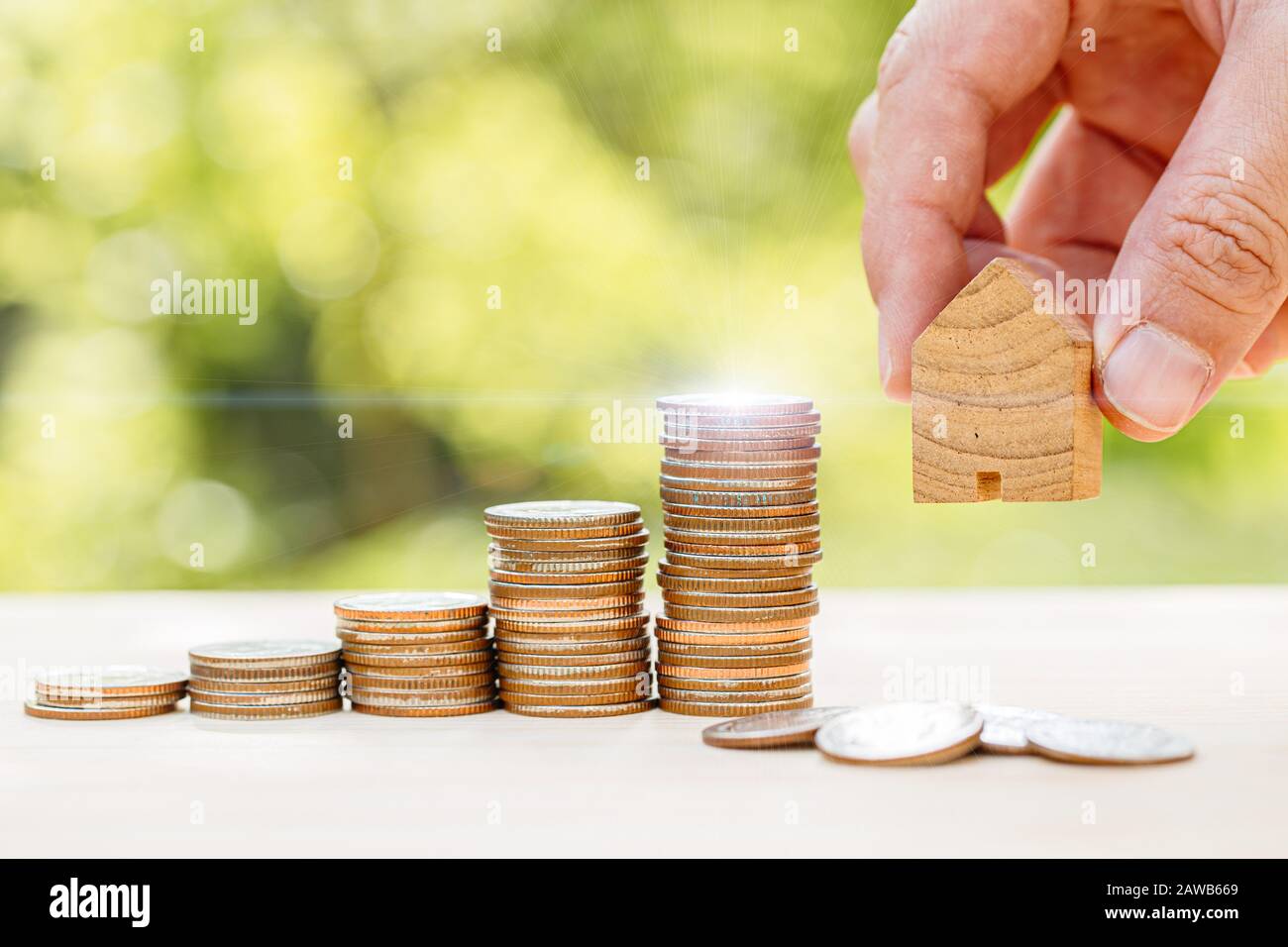 Sparen Sie Geld für den Kauf eines neuen Home Concept, Die Münze wächst aus dem Sparen und halten von kleinen Holzhaus. Stockfoto