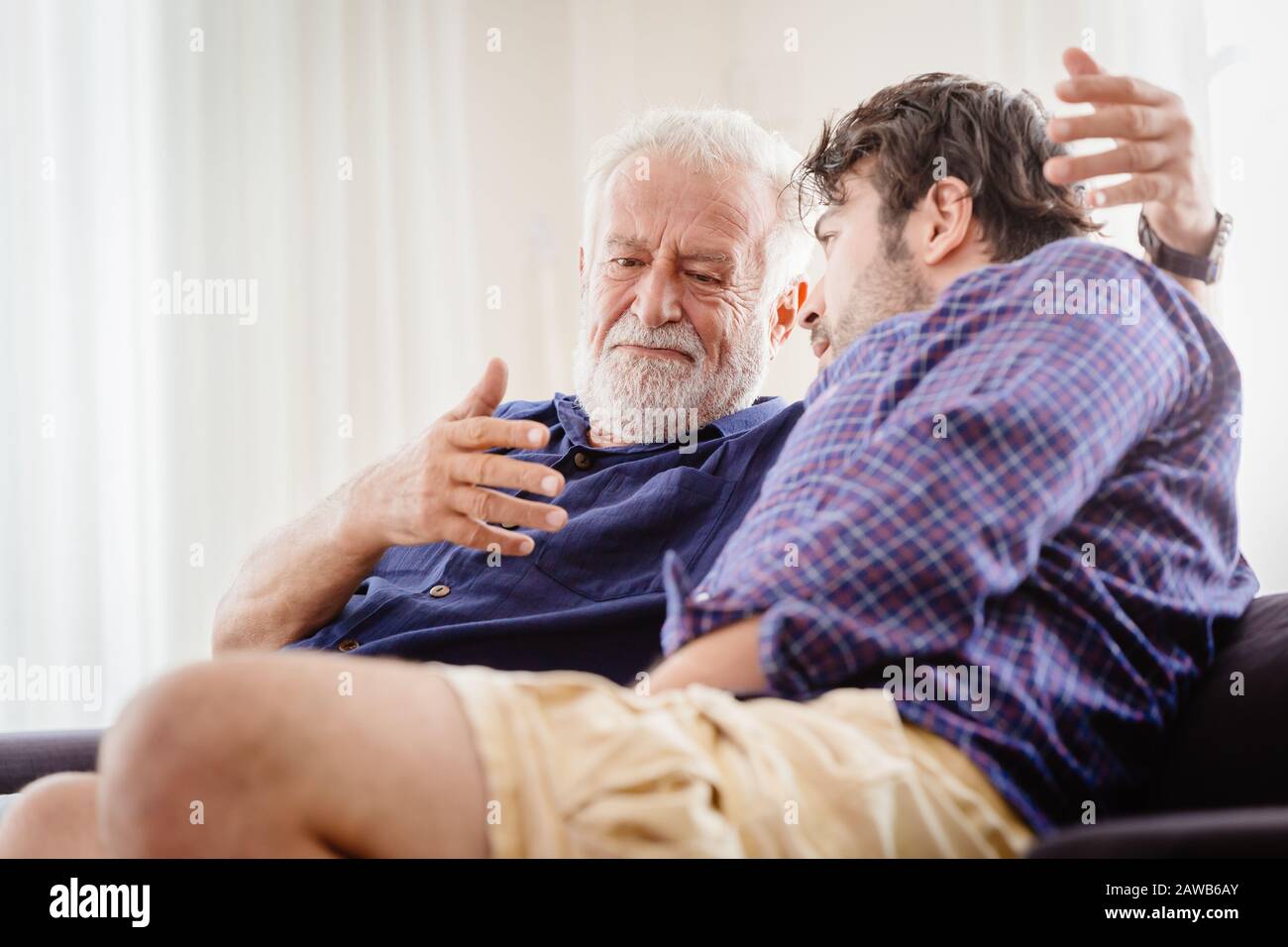Alter Mann ernsthafte Diskussion mit jüngerem Mann im Innenbereich, Großvater ernsthafte Gespräche mit seinem Sohn zu Hause. Stockfoto